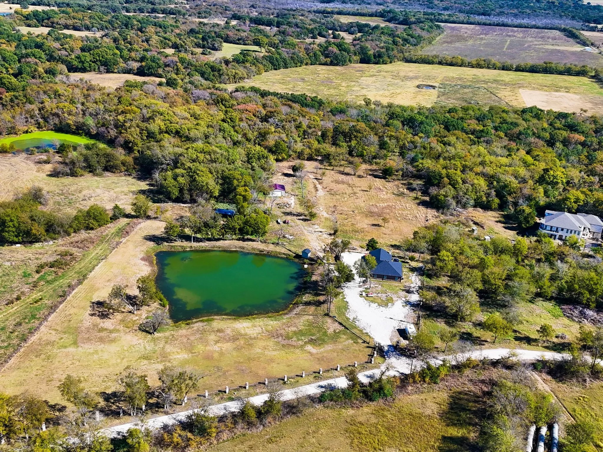 Expansive property with multiple structures, two distinct ponds, and a mix of mature trees and open land
