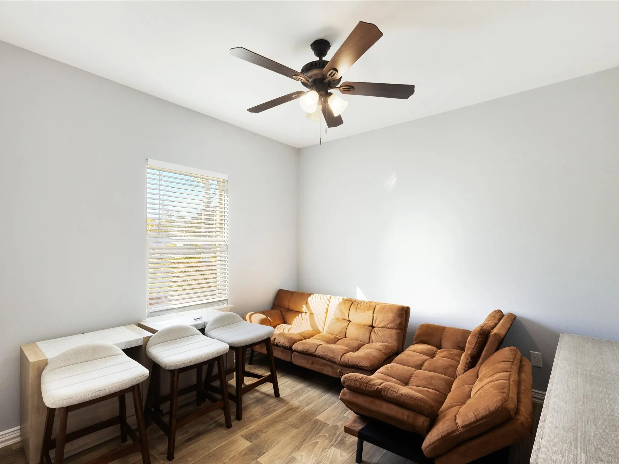 Light wood-finish flooring, single window with blinds, and a built-in ceiling fan with light fixture