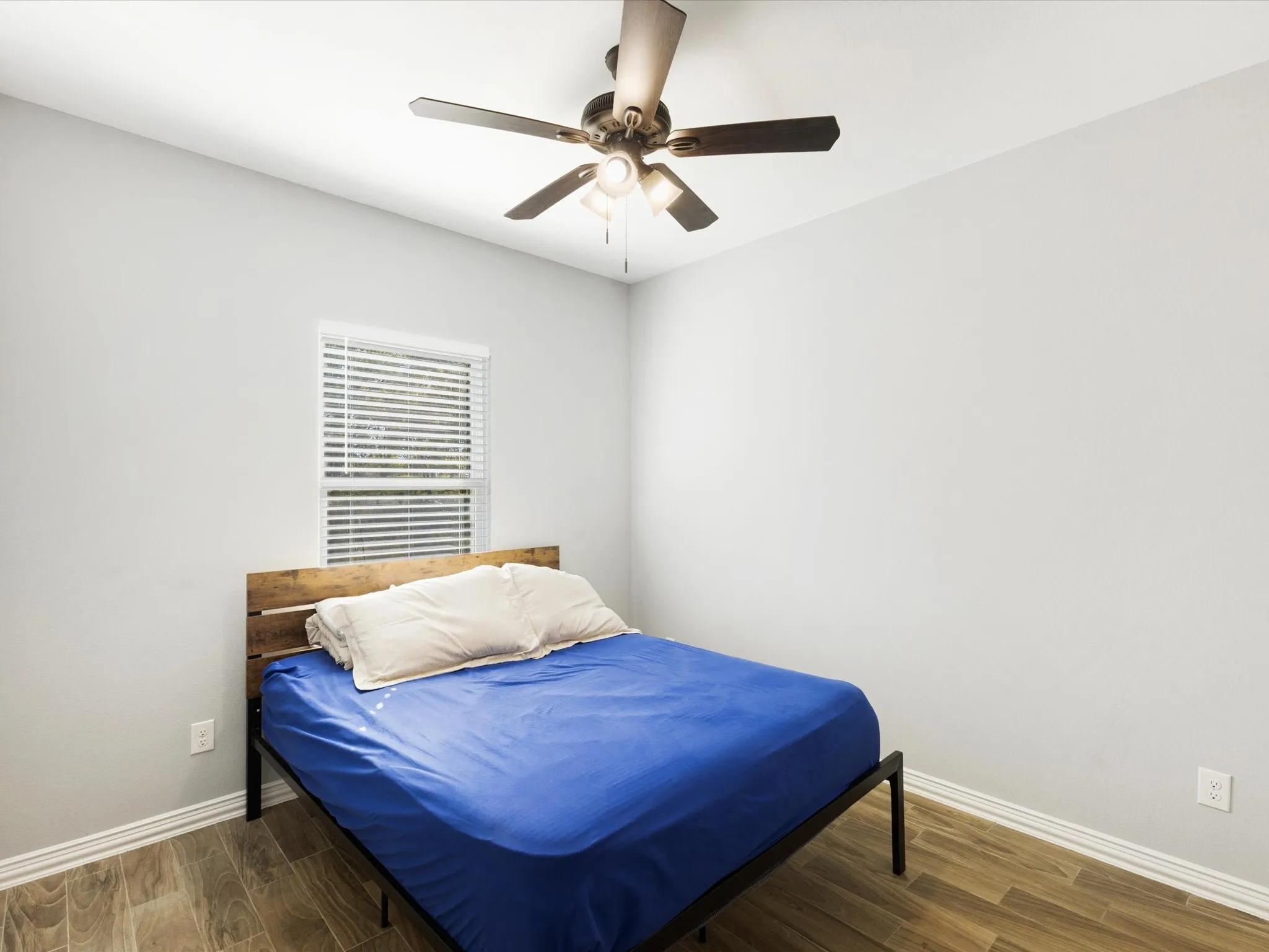 Wood-finish flooring, white walls, and a window with blinds