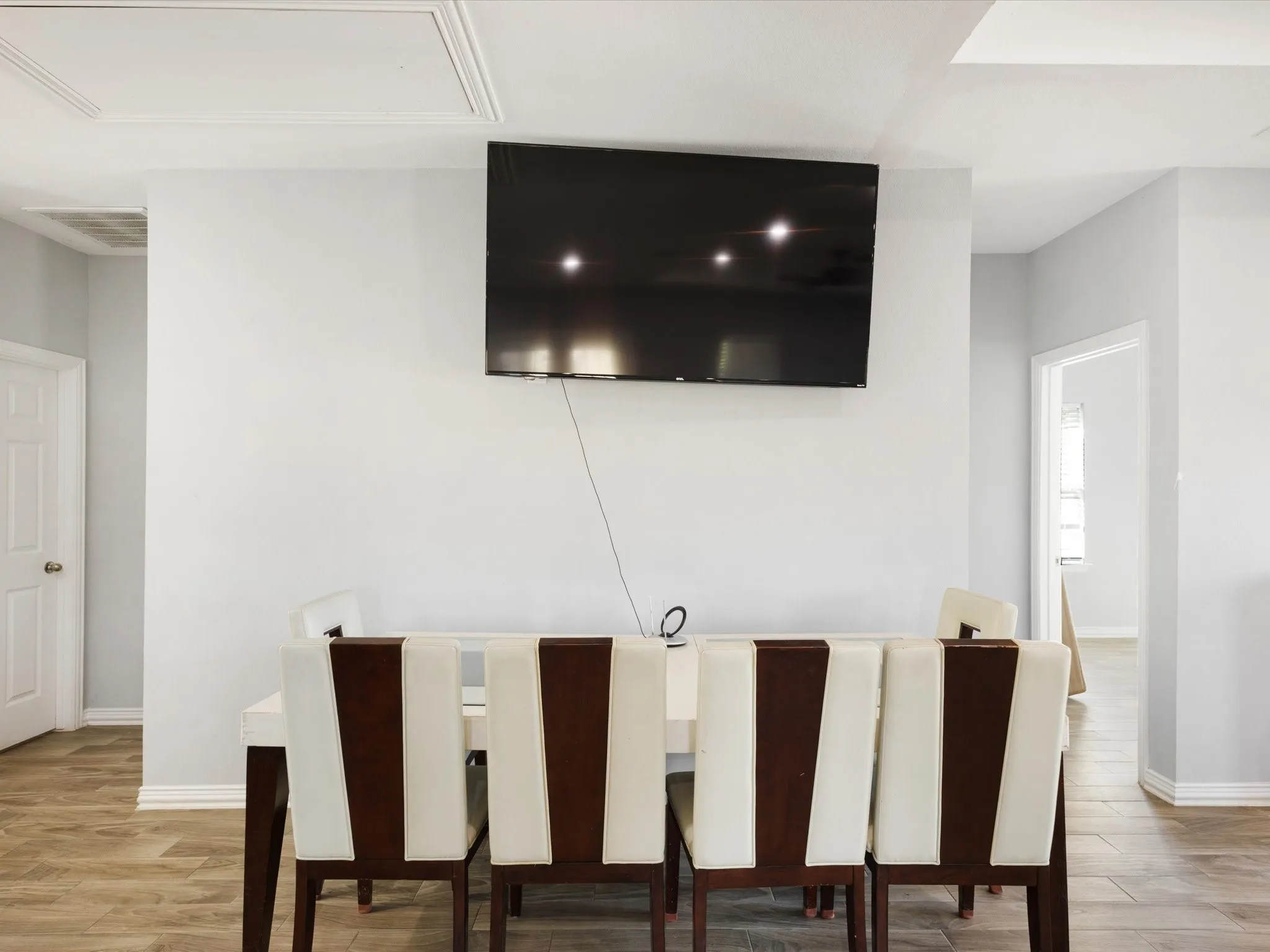 Recessed ceiling panel, crisp white walls, and wood-finish flooring