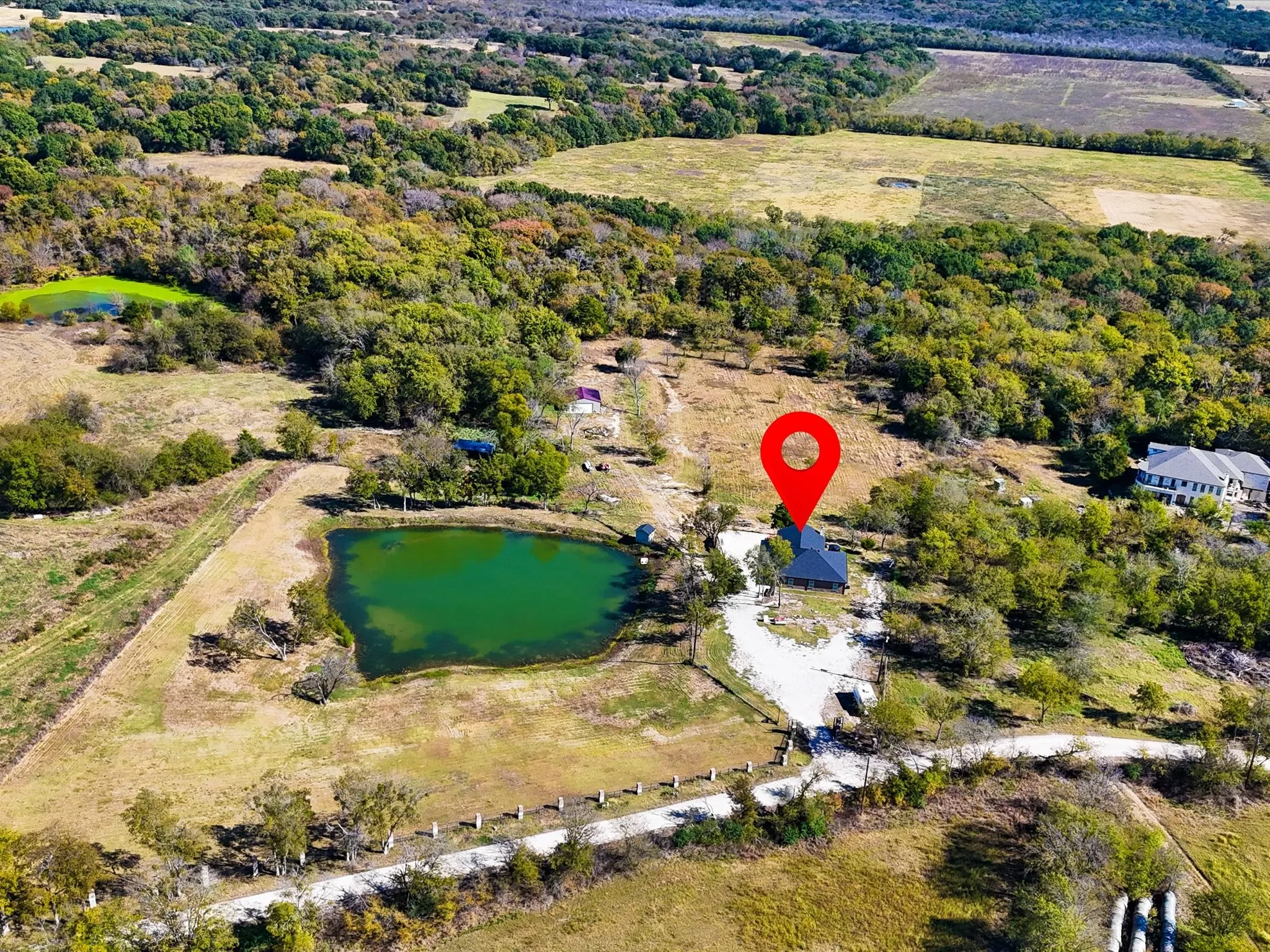 Expansive property featuring a private pond, additional water feature, and a tree-lined landscape