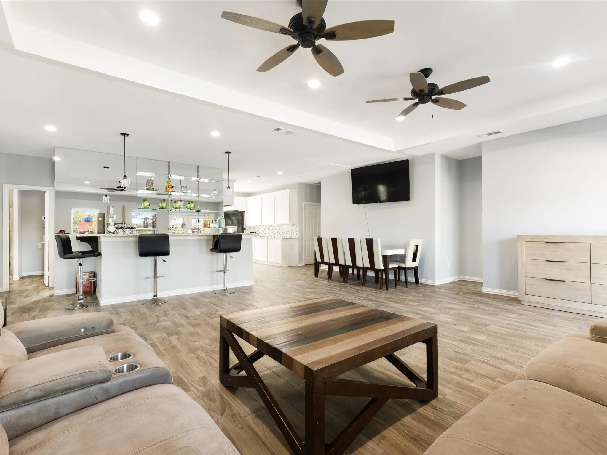 Spacious open-concept living area featuring wood-finish flooring, recessed lighting, and ceiling fans