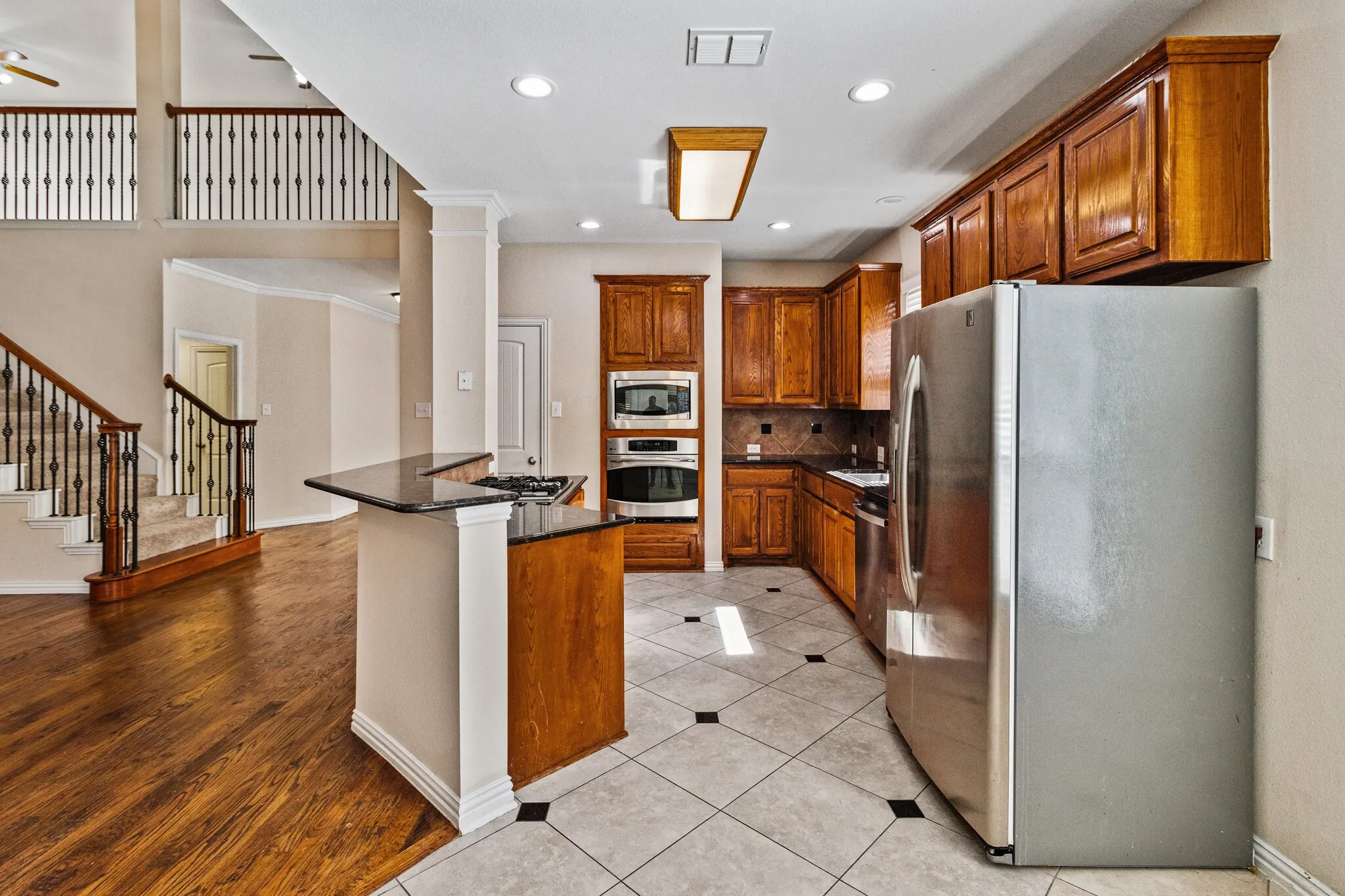 Kitchen with wood-finish cabinetry, stainless steel appliances, and a black countertop island