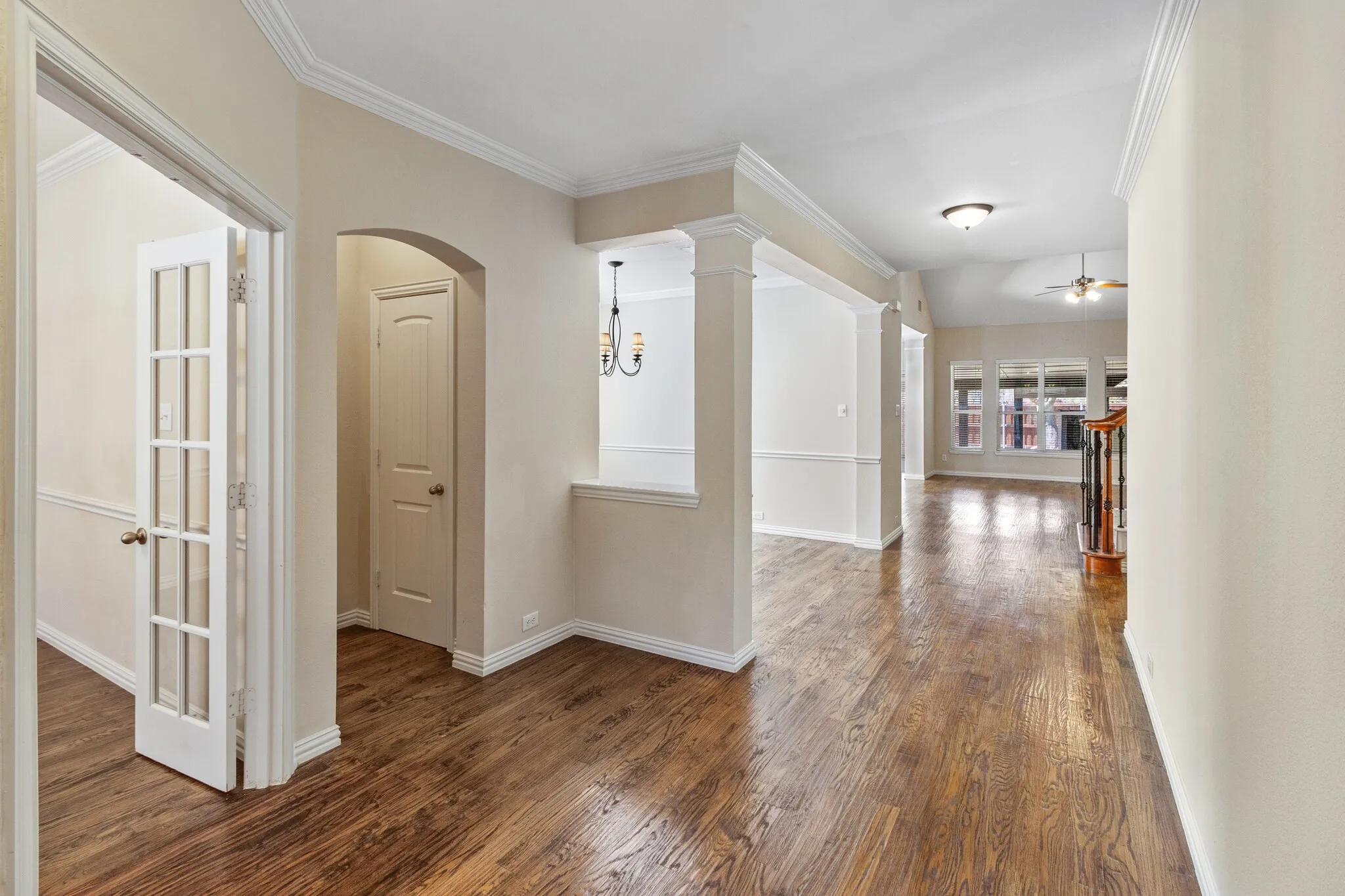 Hardwood-finish flooring throughout, decorative columns, crown molding, and an arched doorway