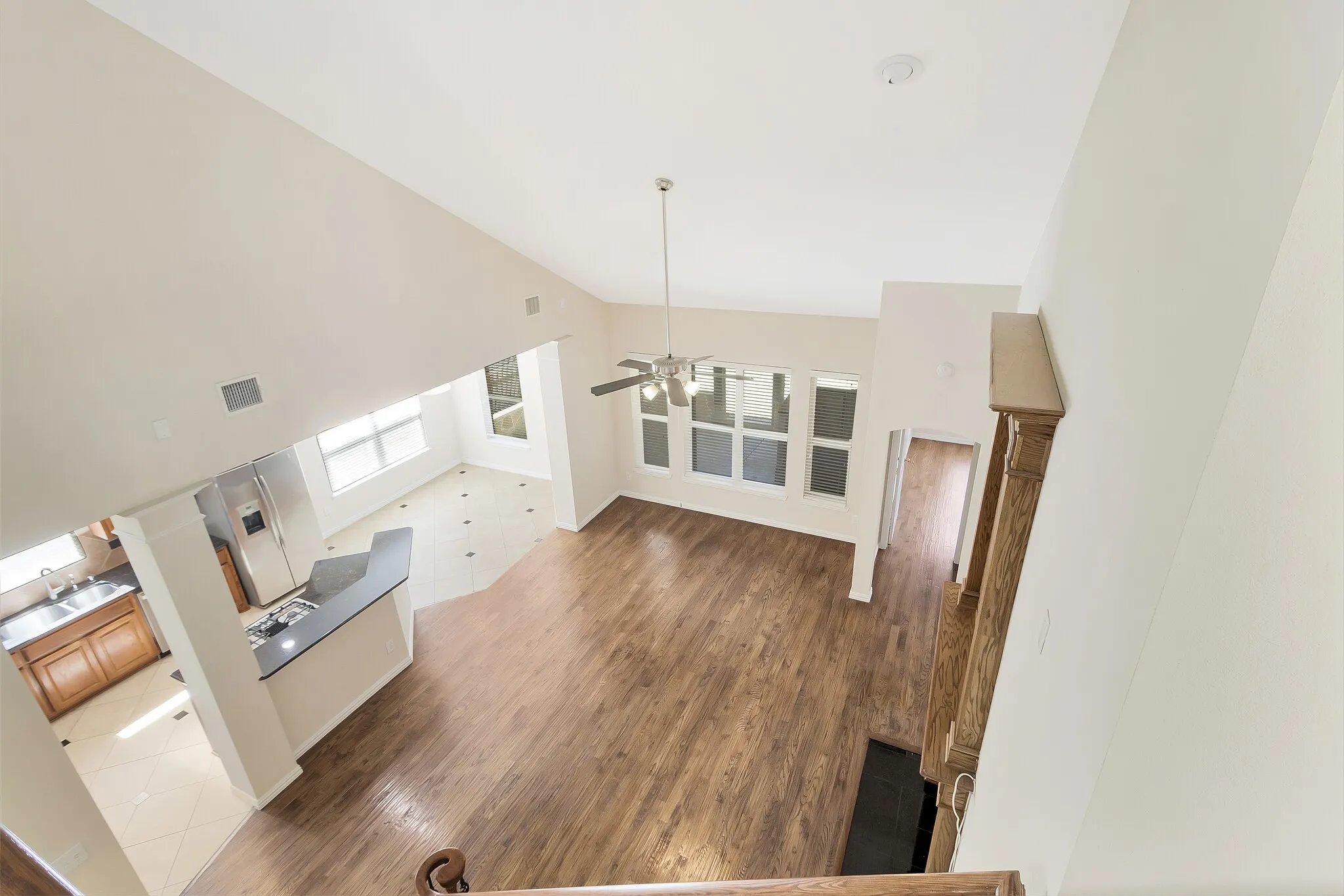 Vaulted ceiling, wood-finish flooring, built-in kitchen island, multiple windows, and a ceiling fan with light fixture