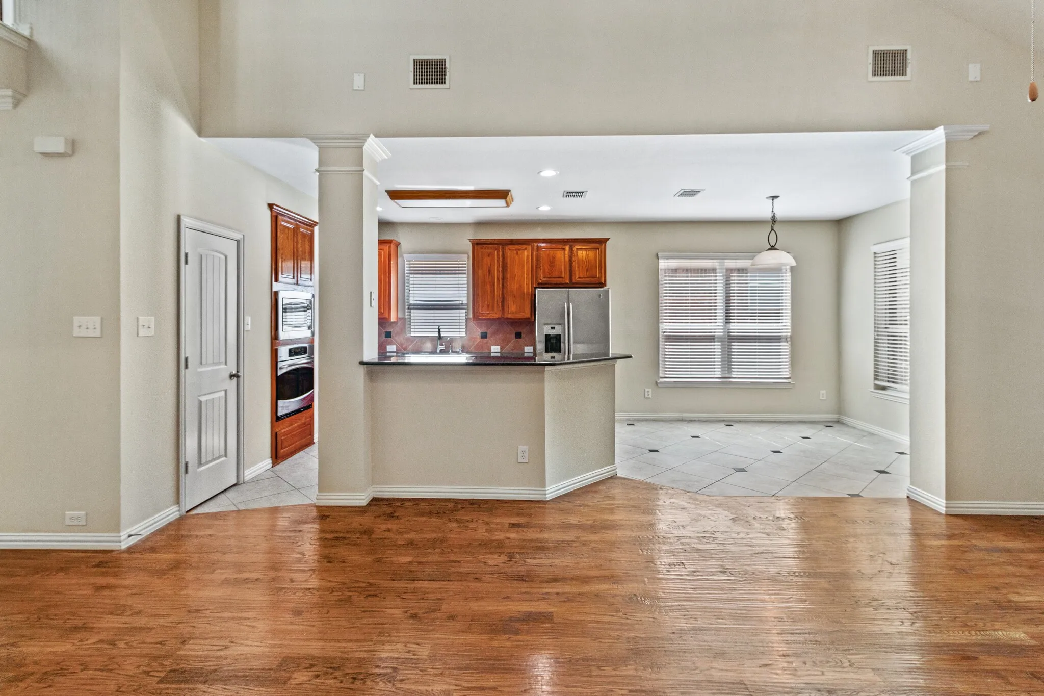 Hardwood flooring, kitchen with wood cabinetry, stainless steel appliances, breakfast bar, and tile flooring