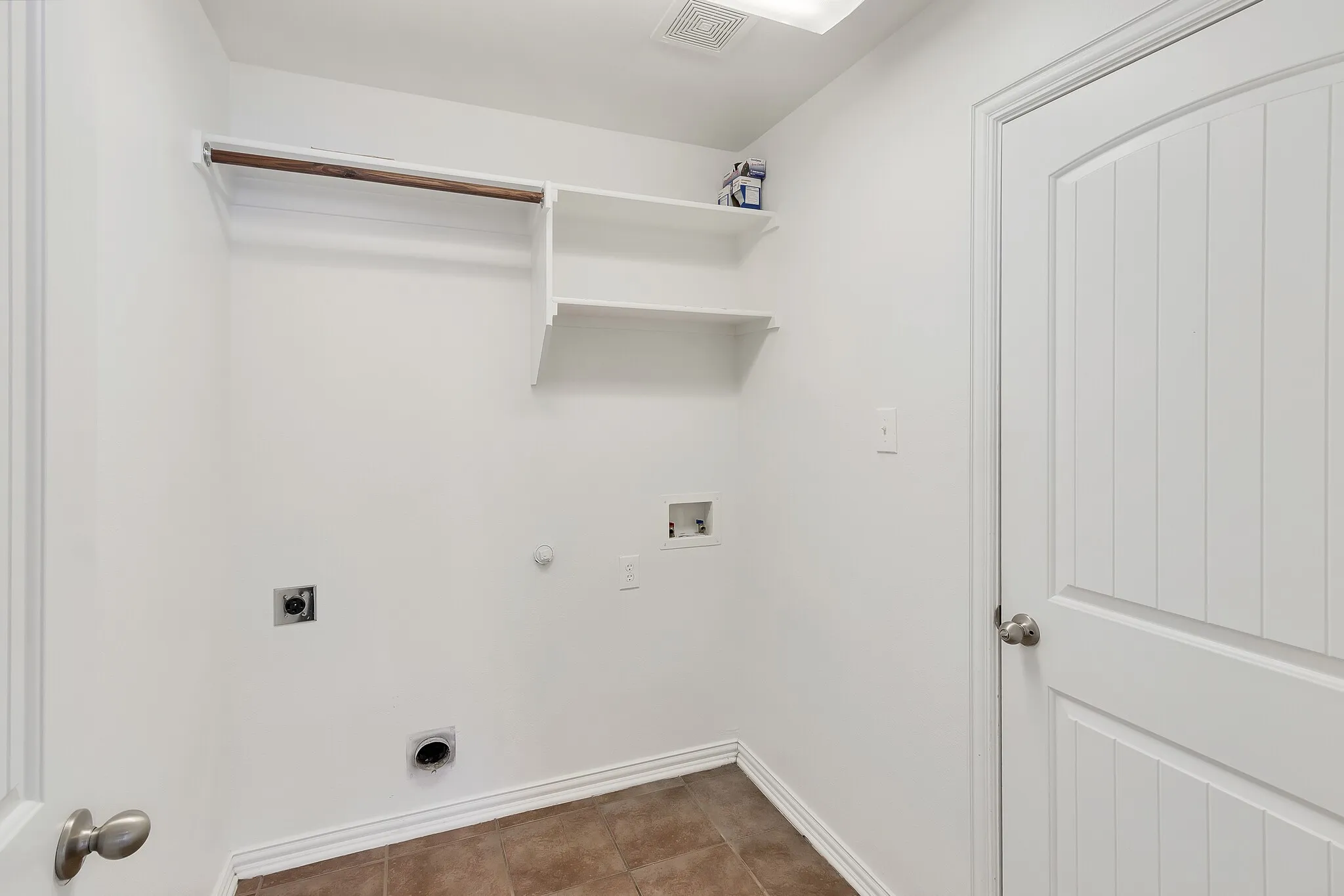 Laundry area featuring a hanging rod, two built-in shelves, and a tile floor