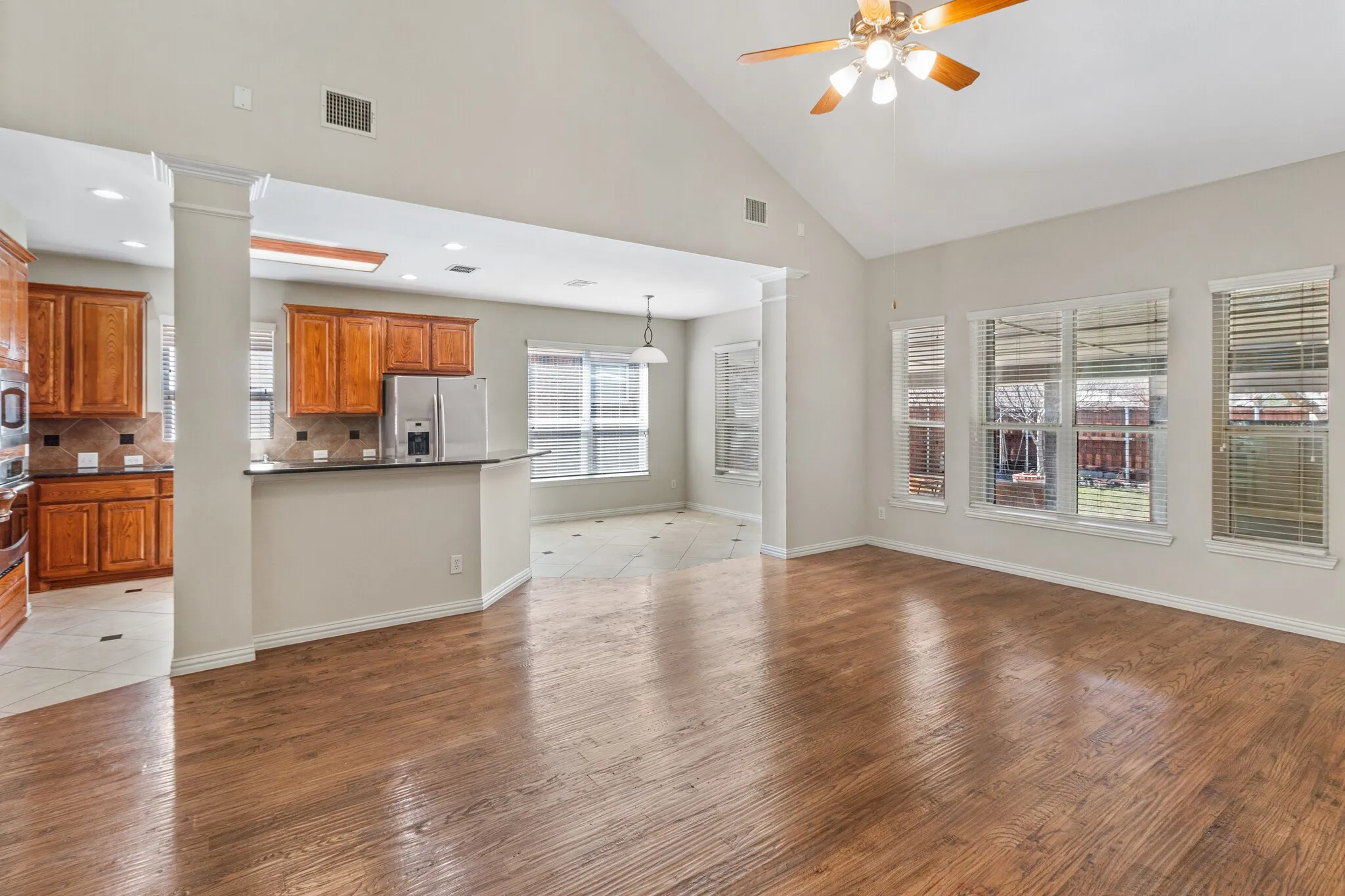 Wood-finish flooring with vaulted ceilings and a ceiling fan