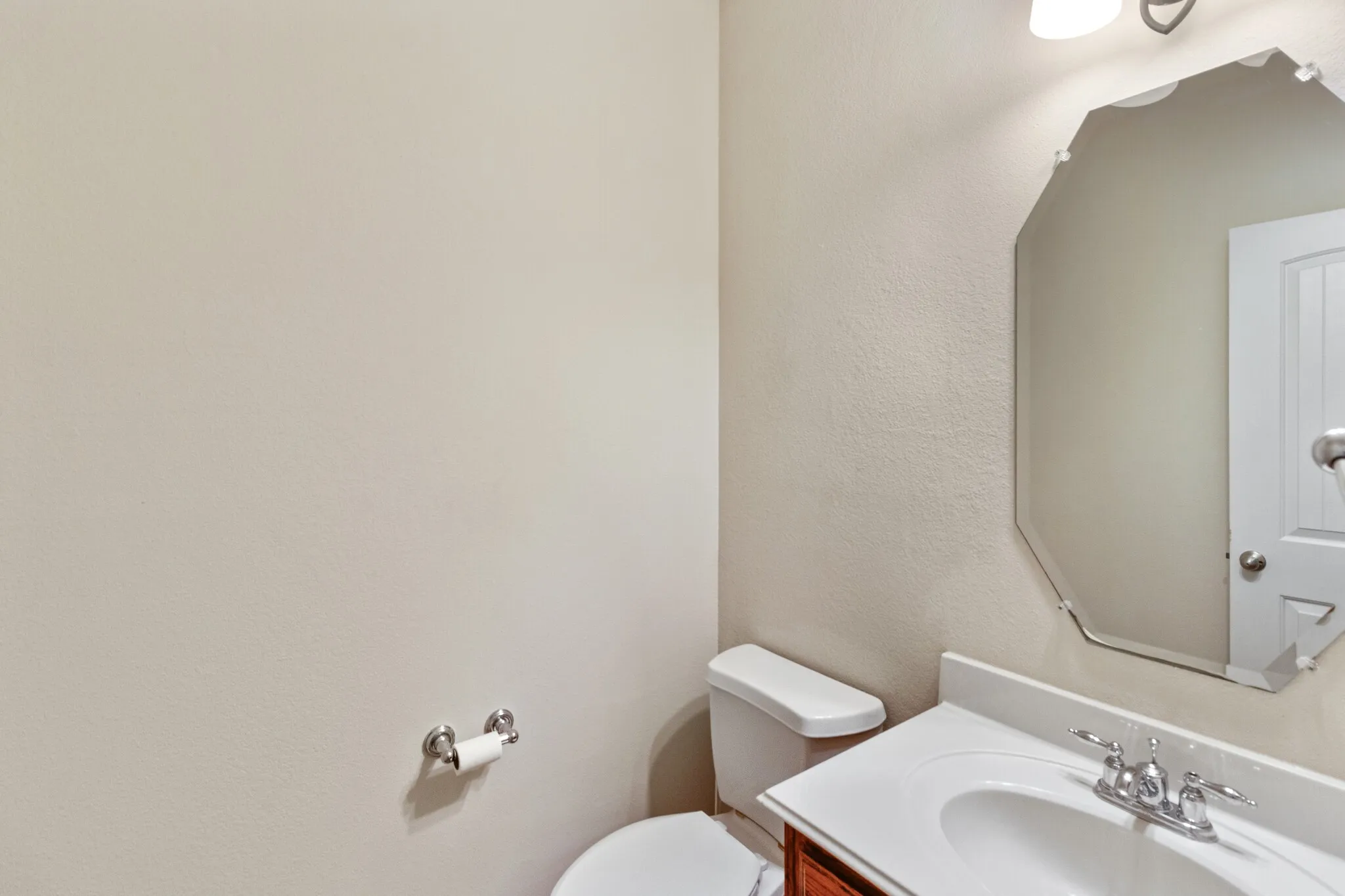 White vanity with integrated sink, chrome faucet, and wood-finish cabinetry