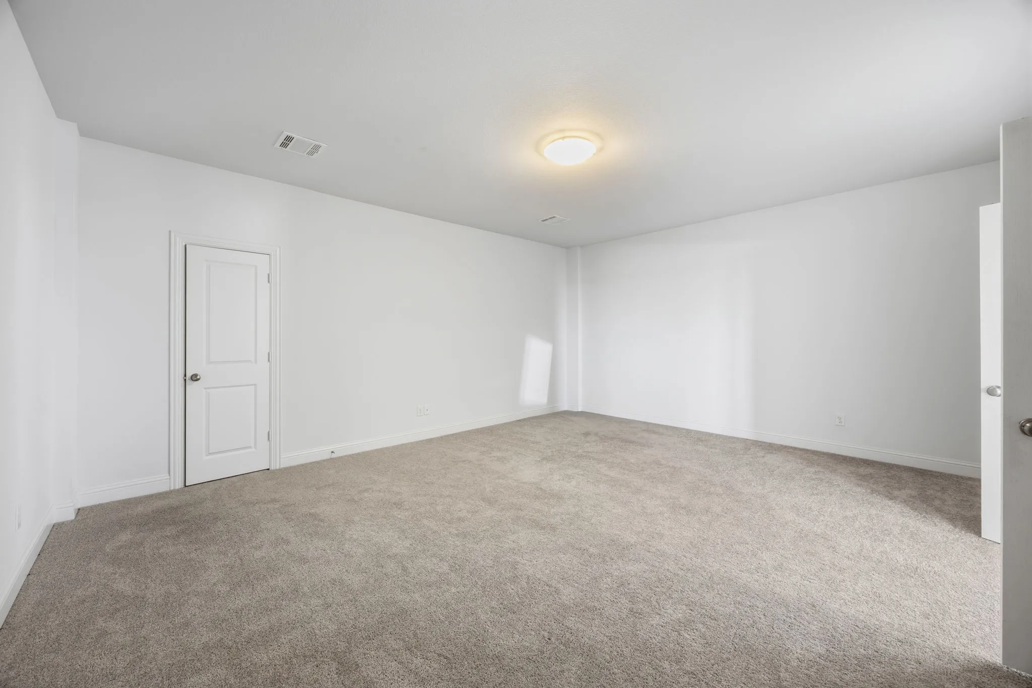Recessed ceiling light, neutral wall paint, and gray carpeted flooring