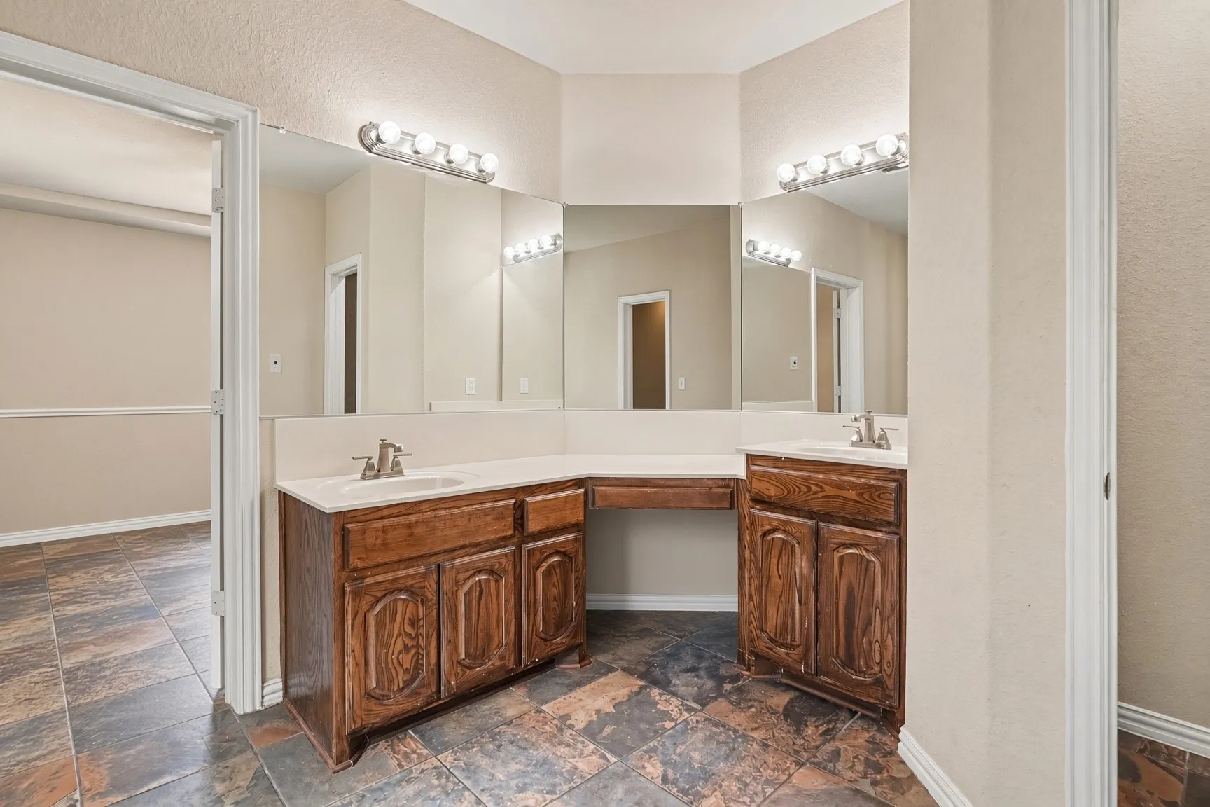 Dual vanity with wood-finish cabinetry, integrated sinks, chrome faucets, and tile flooring