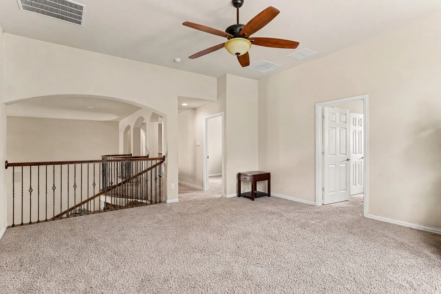 Arched openings, wrought iron railing, and a ceiling fan with integrated lighting