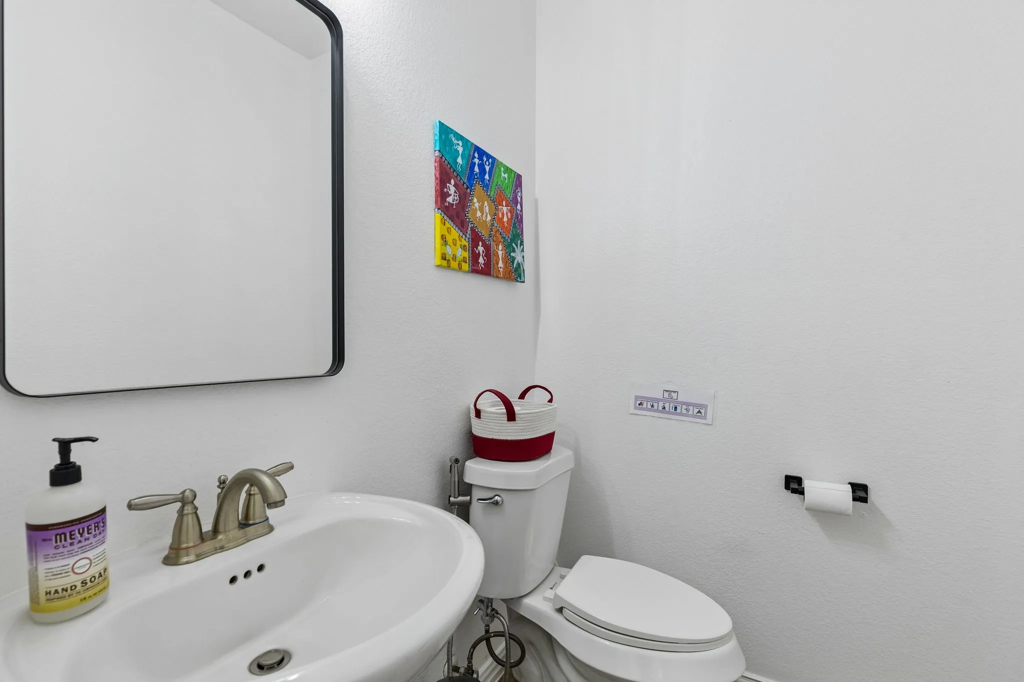 Vanity with an integrated sink basin, dual-handle faucet, and black-framed mirror