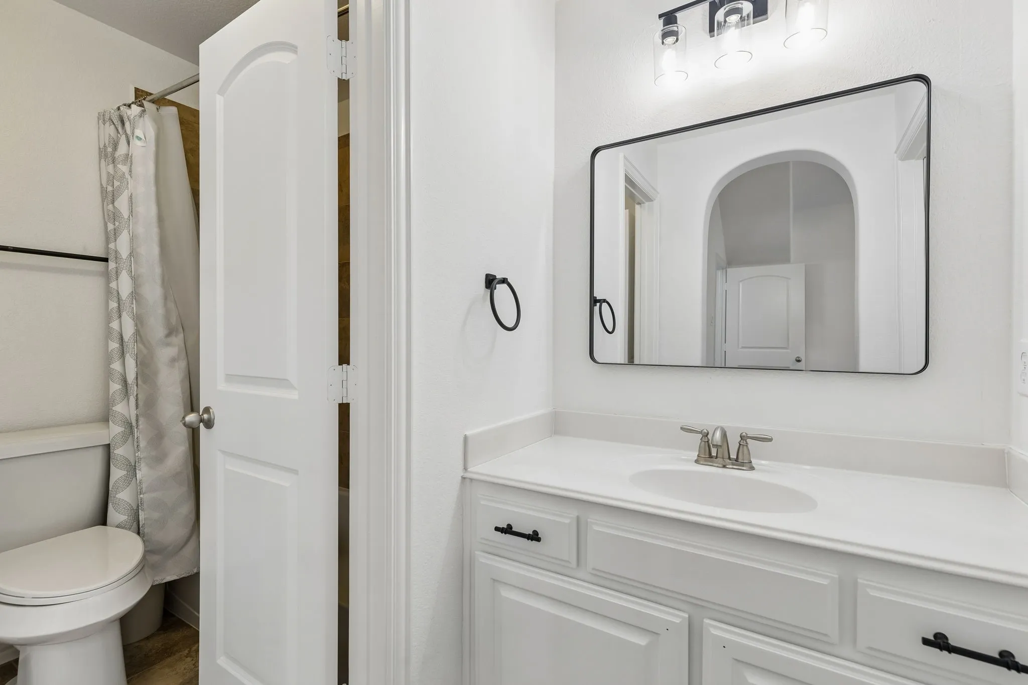 White vanity with an integrated sink, brushed nickel faucet, and matte black hardware