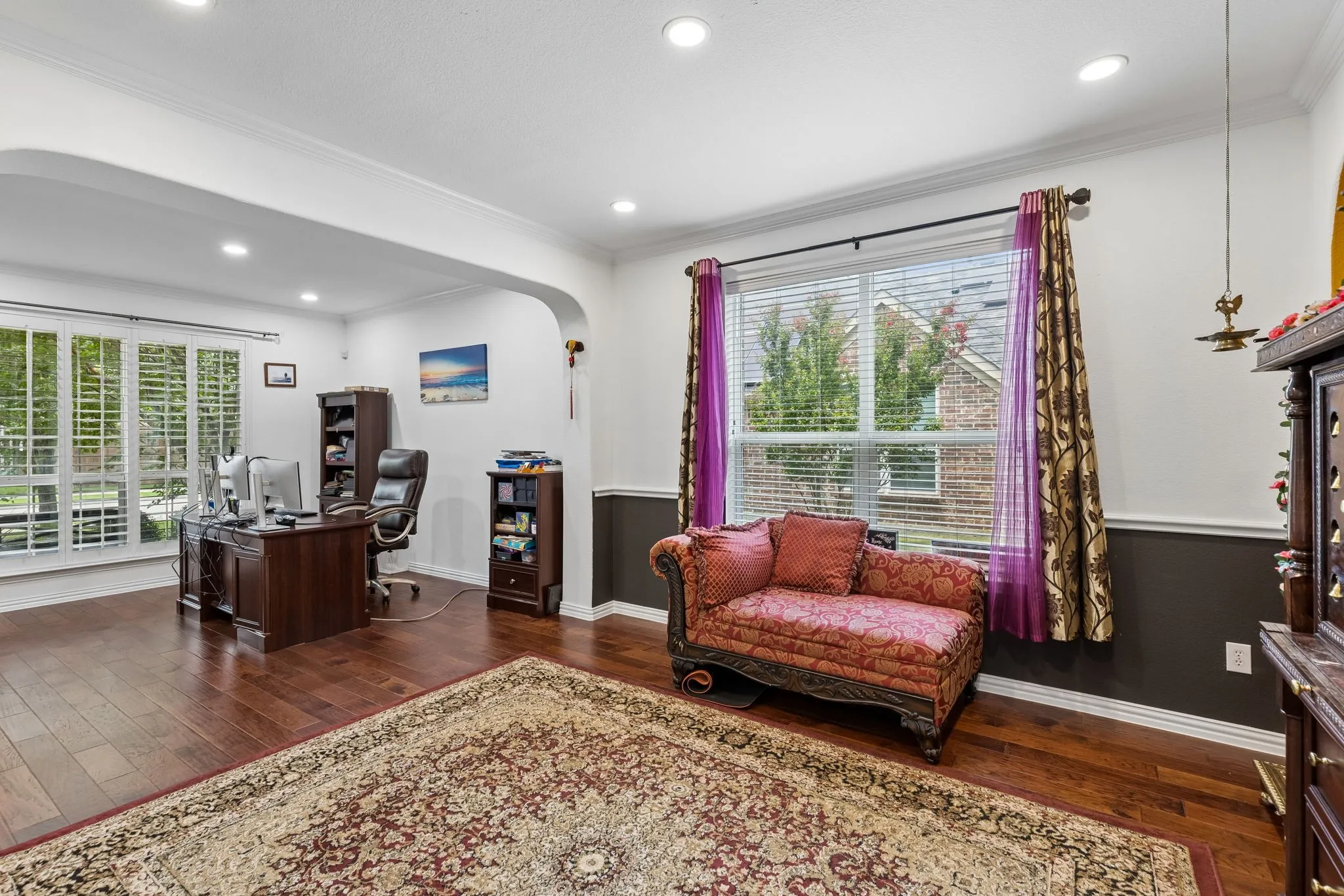 Wood-finish flooring, recessed lighting, arched doorway, window with plantation shutters, and crown molding