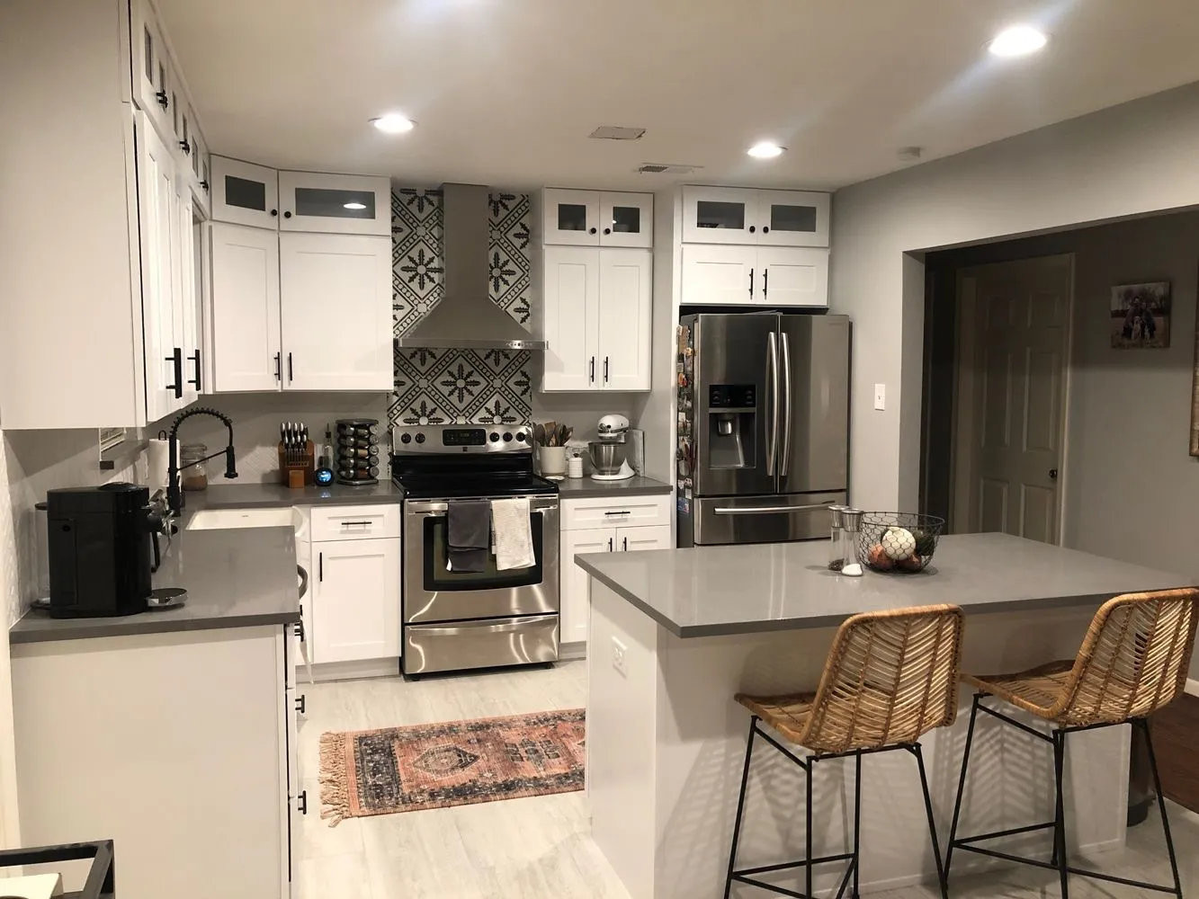 White shaker cabinetry with dark hardware, stainless steel appliances, patterned backsplash, grey countertops, and recessed lighting
