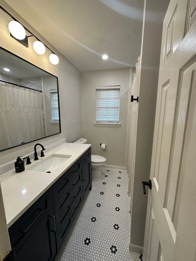 Bathroom featuring a dark wood finish vanity with integrated sink, white countertop, and matte black fixtures