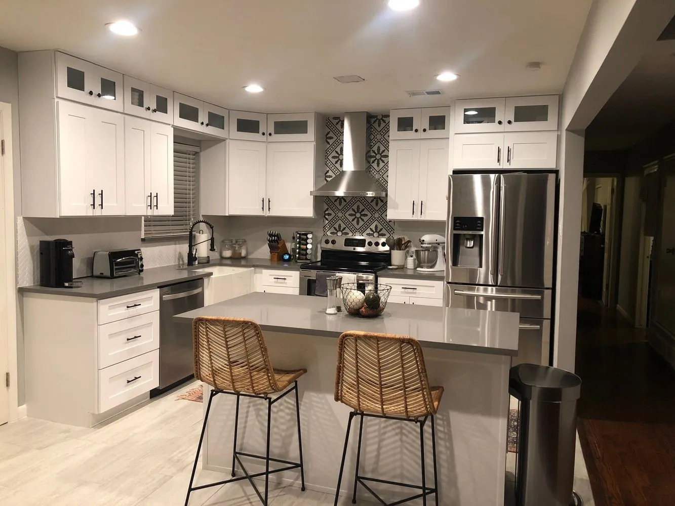 Kitchen featuring white cabinetry, gray countertops, stainless steel appliances, a corner range hood with decorative tile backsplash, and light wood-finish flooring