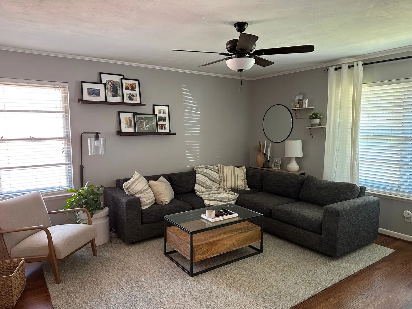 Expansive living area with a dark-tone ceiling fan light fixture, light gray walls, and rich wood-finish flooring