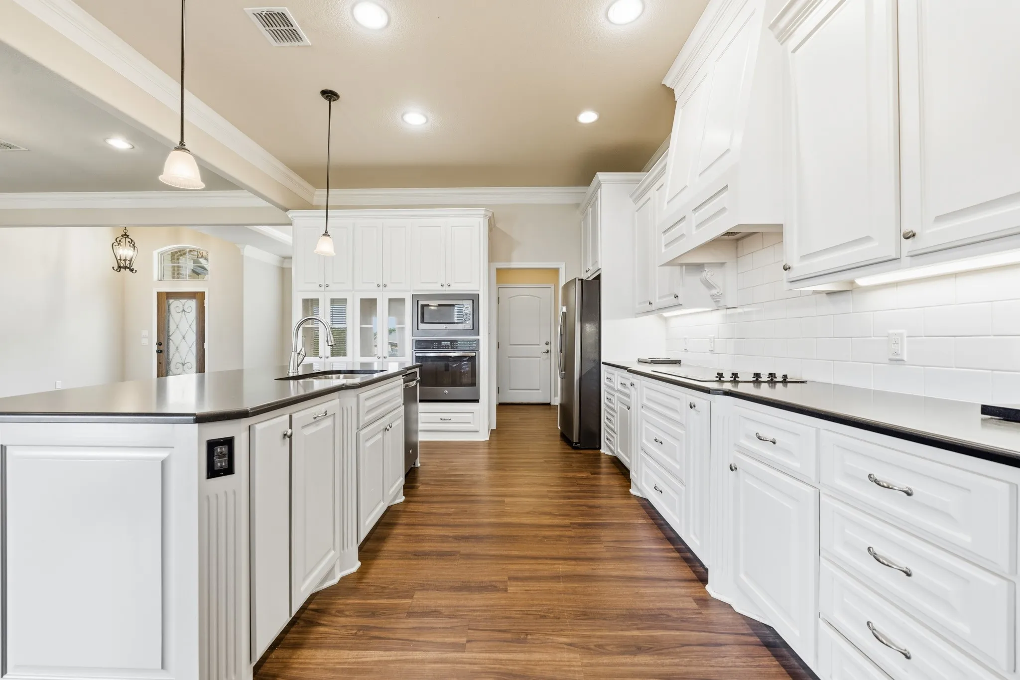 Spacious kitchen featuring abundant white cabinetry, stone countertops, and a subway tile backsplash