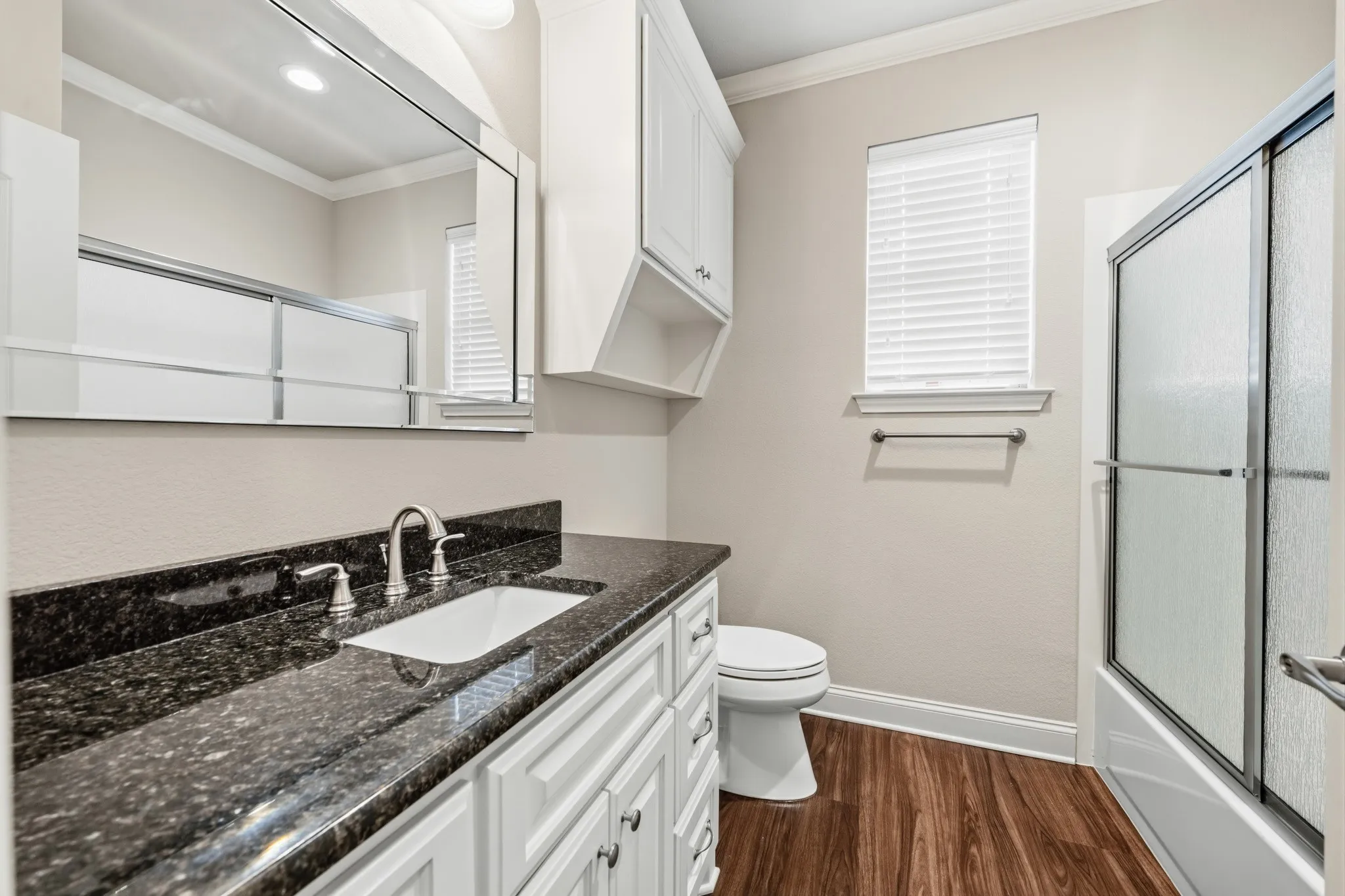 White shaker-style vanity with a dark granite countertop and undermount sink