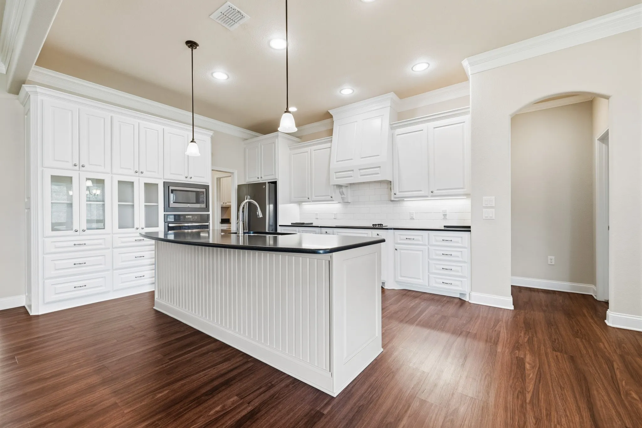 Kitchen featuring white cabinetry, stone countertops, recessed lighting, and a kitchen island with pendant lighting