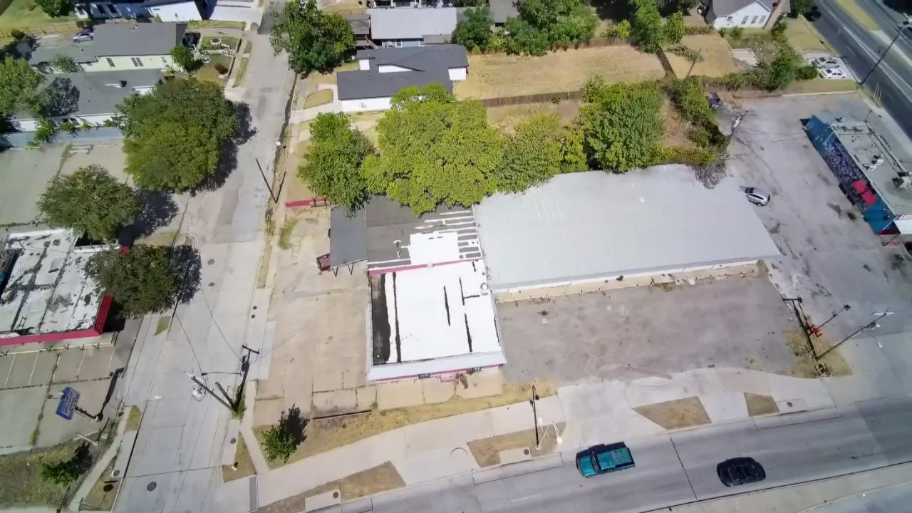 Building with a metal roof, an adjacent flat-roofed structure, and a paved lot