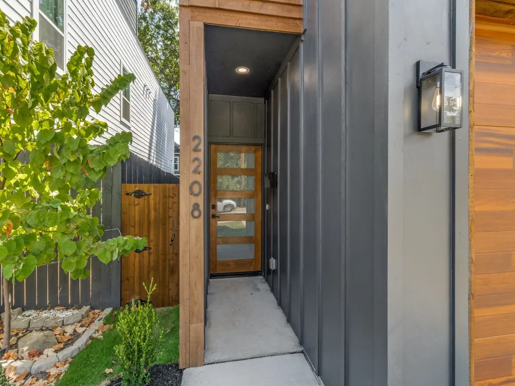 Entryway featuring a wood-panel door with privacy glass, recessed lighting, and a contemporary exterior sconce