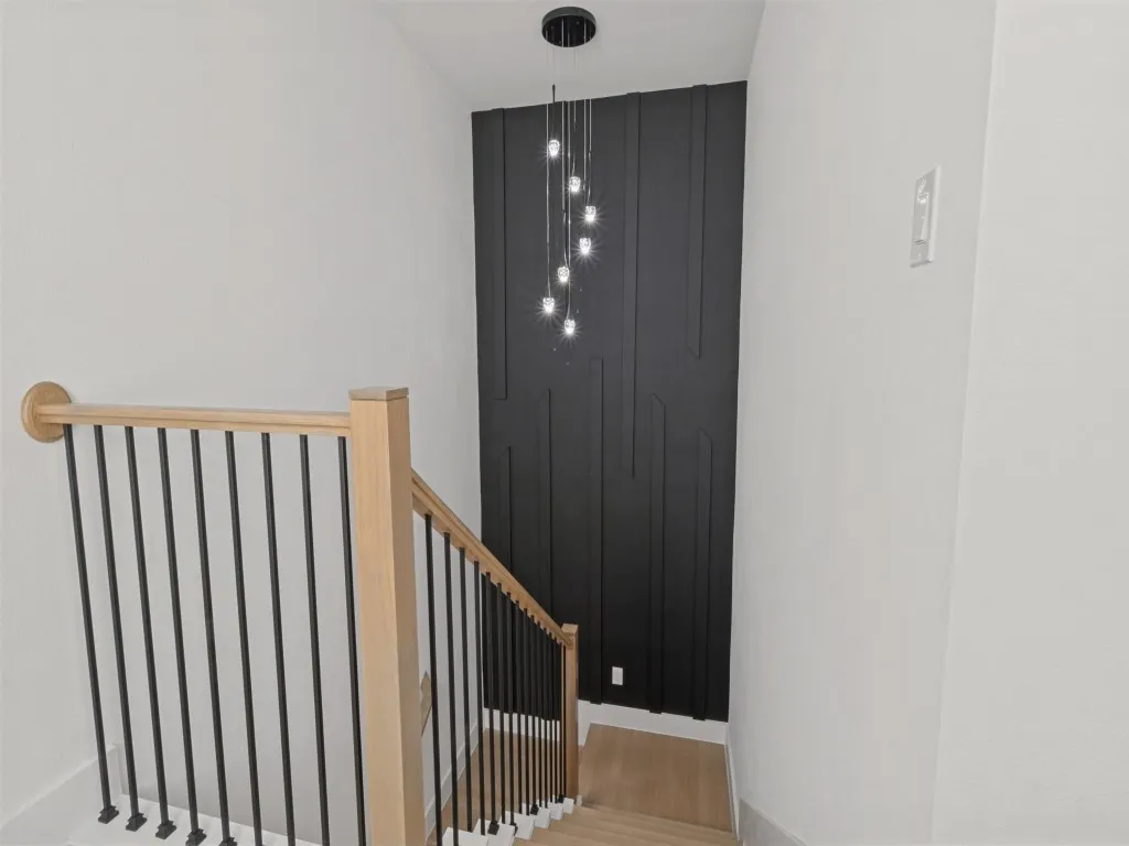 Wood-finish flooring with a modern staircase featuring black metal spindles and light-toned wood handrails