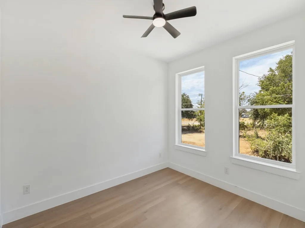 Bright room featuring two large windows, a ceiling fan, and wood-finish flooring