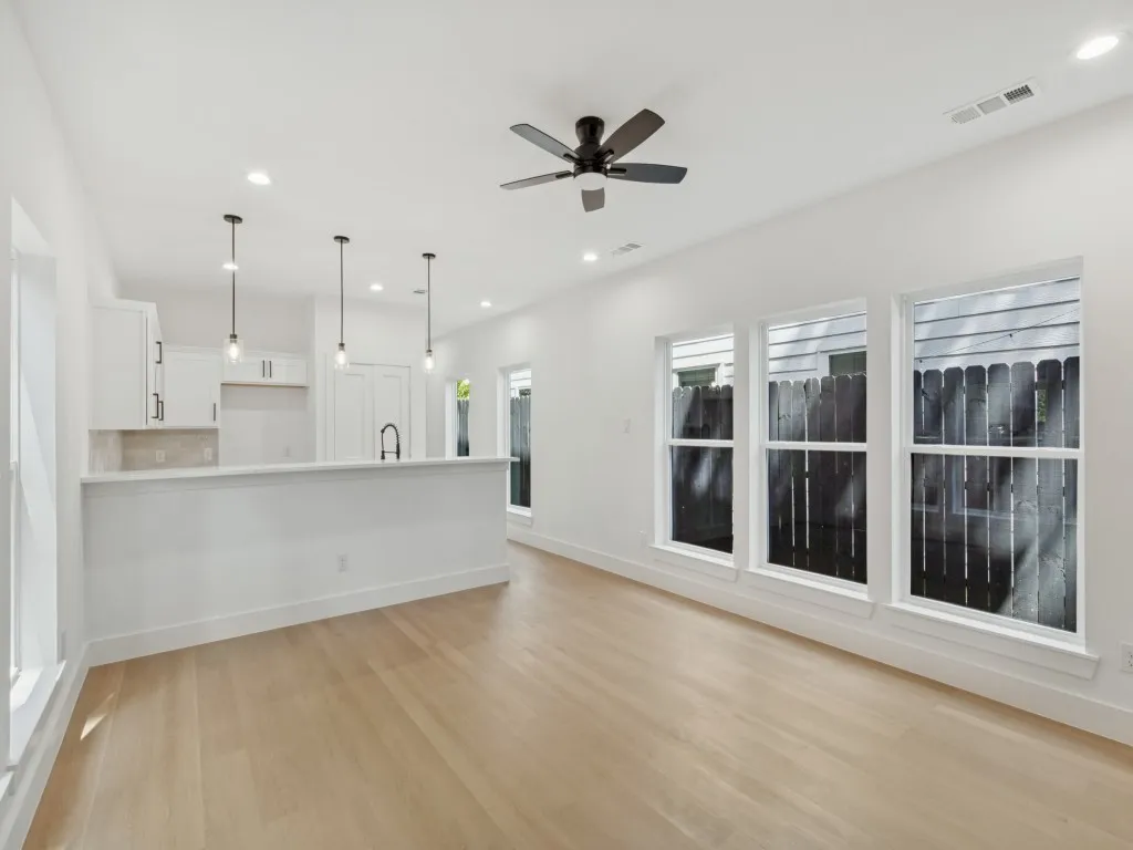 Light wood-finish flooring throughout, white walls, and built-in recessed lighting