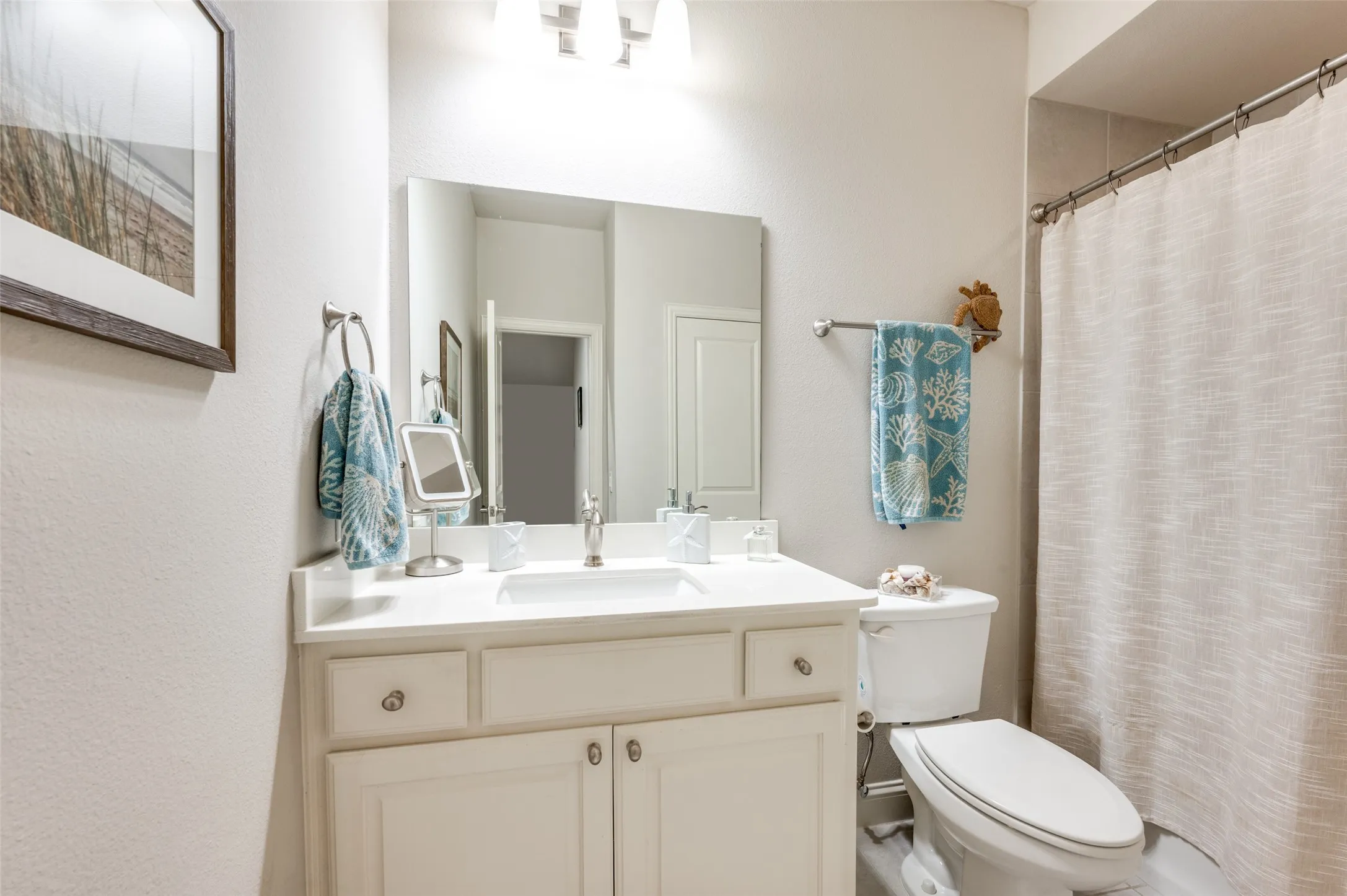 White vanity with an integrated sink, polished chrome faucet, and overhead light fixture