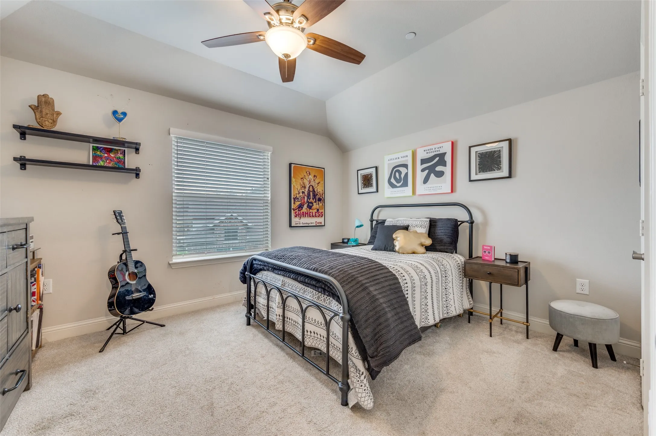Carpeted room featuring a ceiling fan with light fixture, a window with blinds, and two wall-mounted shelves