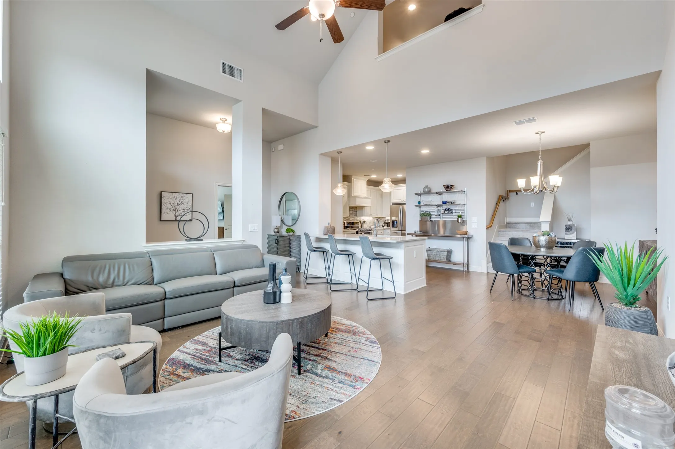 Vaulted ceilings with a ceiling fan, recessed lighting, wood-finish flooring, a kitchen island with seating, and a dining area with chandelier