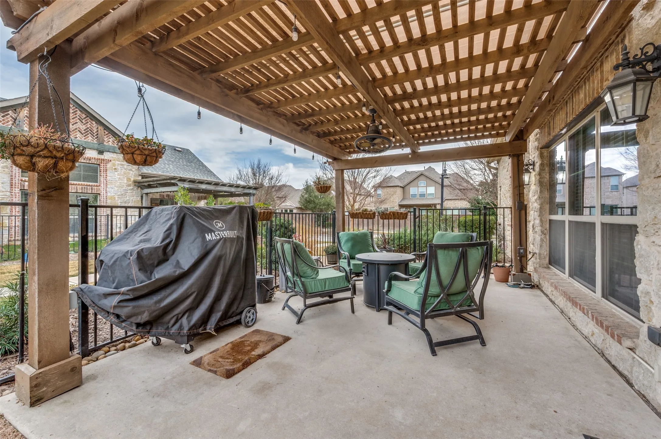Covered patio featuring a wood pergola, concrete flooring, exterior stone wall, and decorative outdoor lighting