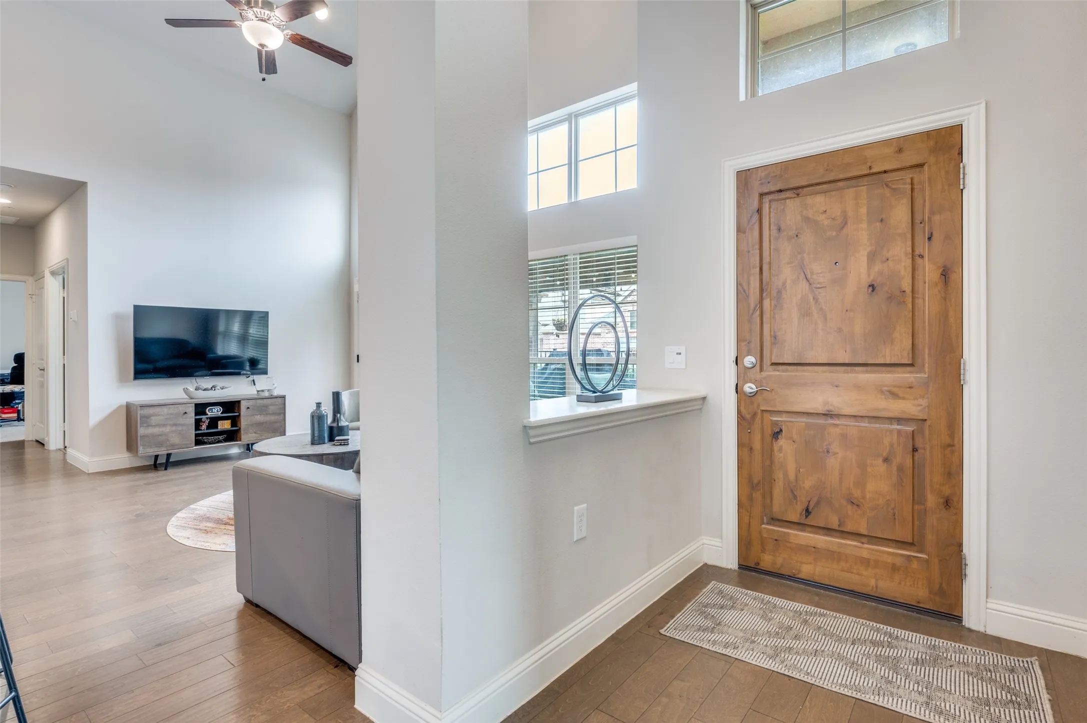 Wood-finish flooring throughout, vaulted ceilings, and a paneled wood-finish entry door with transom window