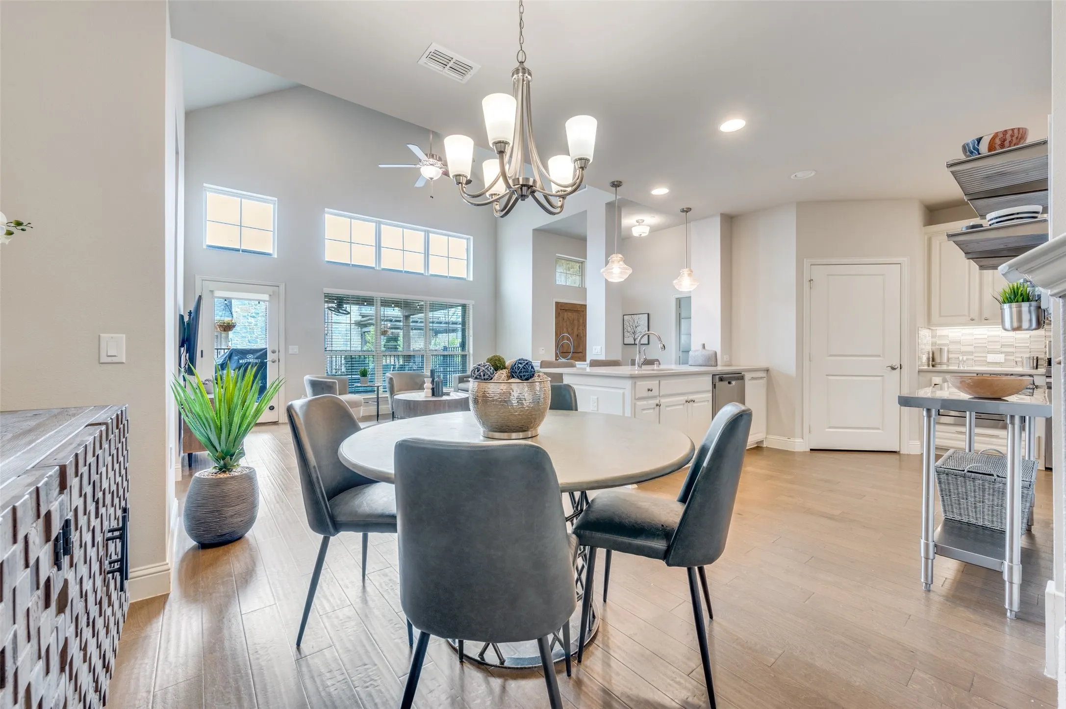 Vaulted ceilings with an elegant chandelier, wood-finish flooring, recessed lighting, and a kitchen island with pendant lighting