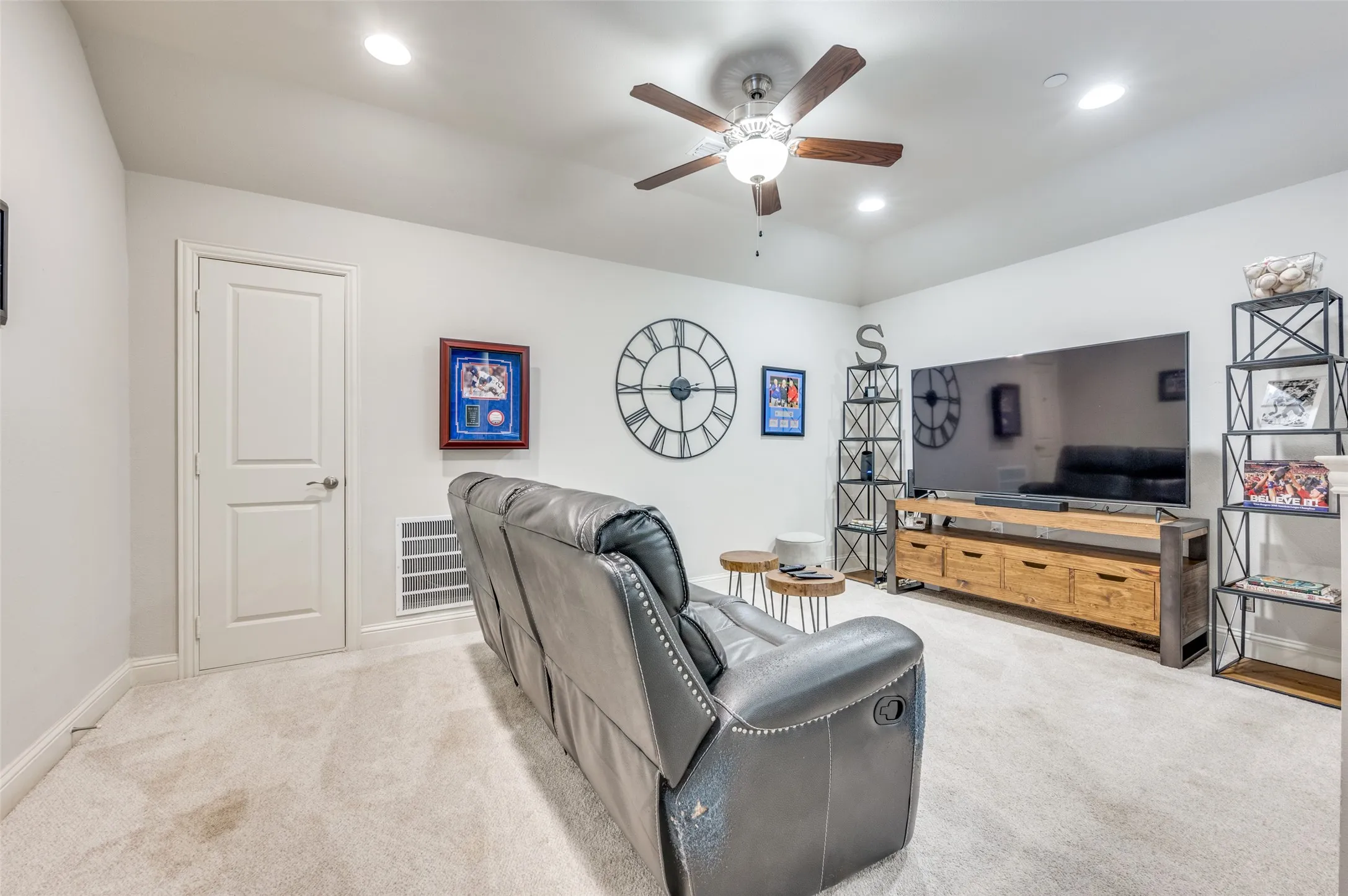 Carpeted room featuring a ceiling fan with light, recessed lighting, and a built-in media console with storage