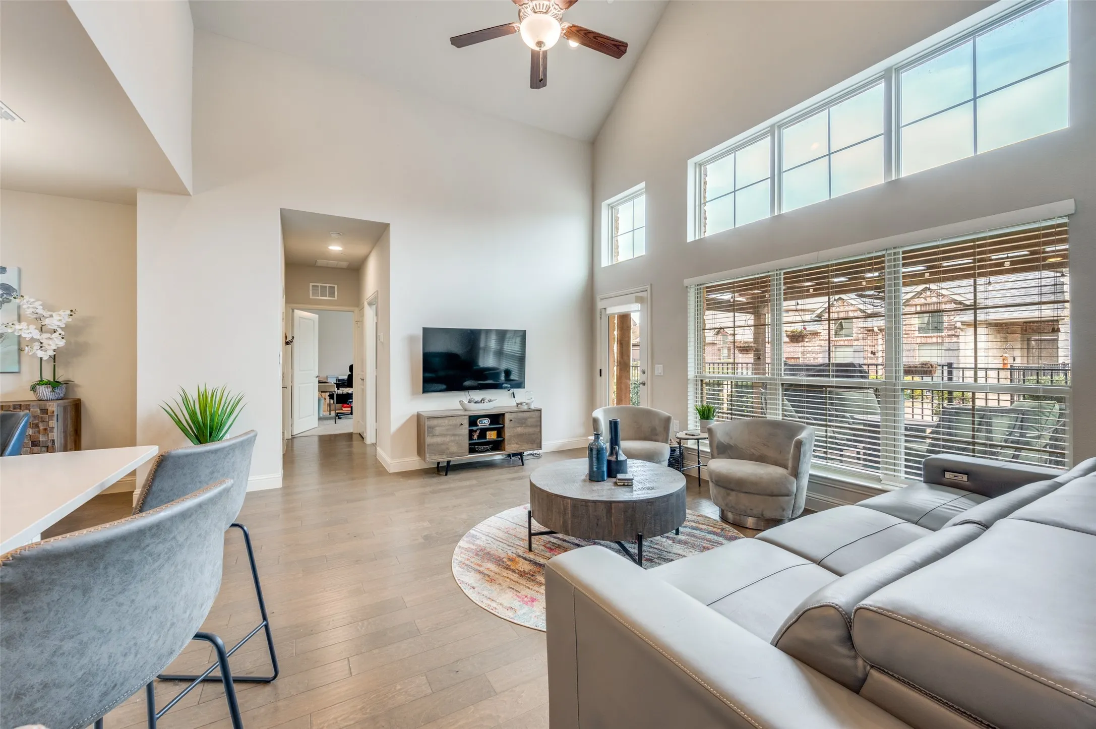 Vaulted ceilings with a ceiling fan, expansive windows, wood-finish flooring, and a built-in media console