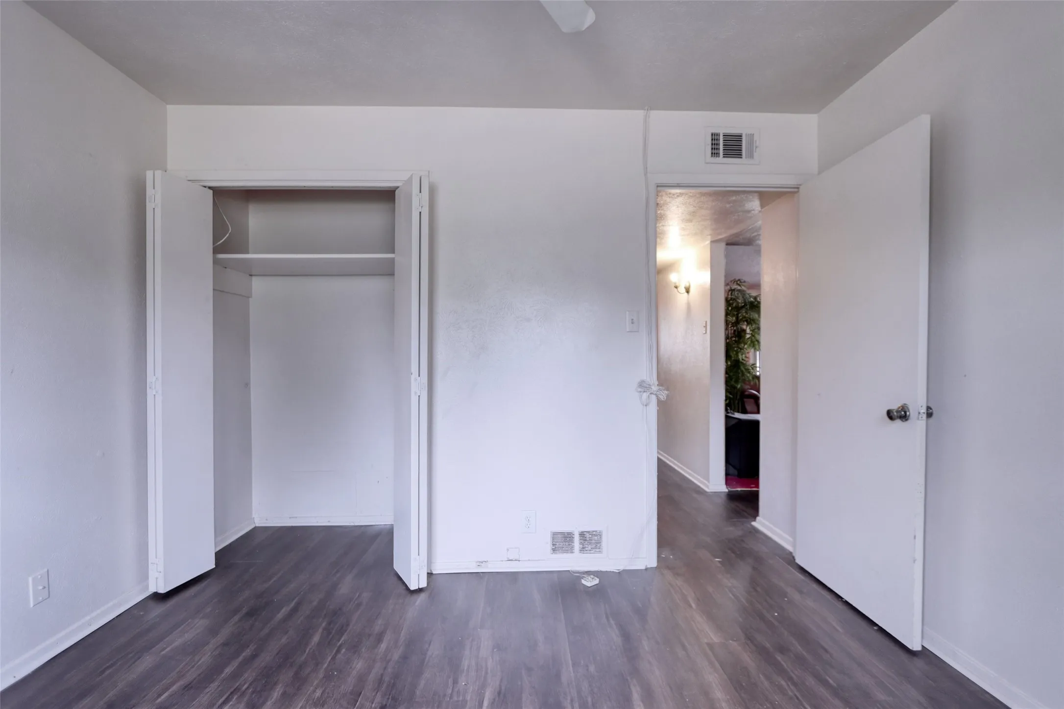 Wood-finish flooring, white walls, and a built-in closet with bi-fold doors