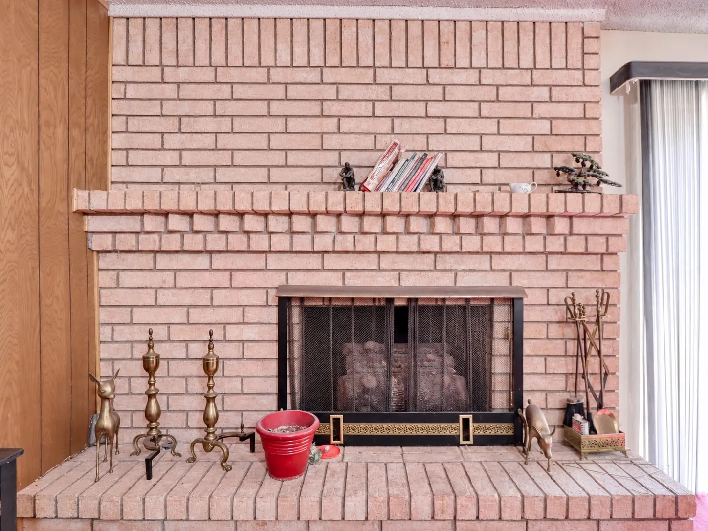 Brick fireplace with an integrated mantel and hearth, featuring a metal firebox screen