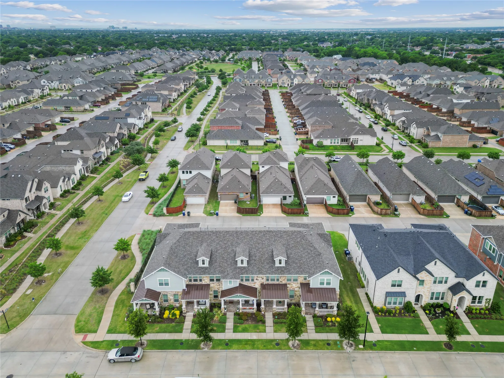 Expansive residential development featuring numerous single-family homes and townhomes, surrounded by mature trees