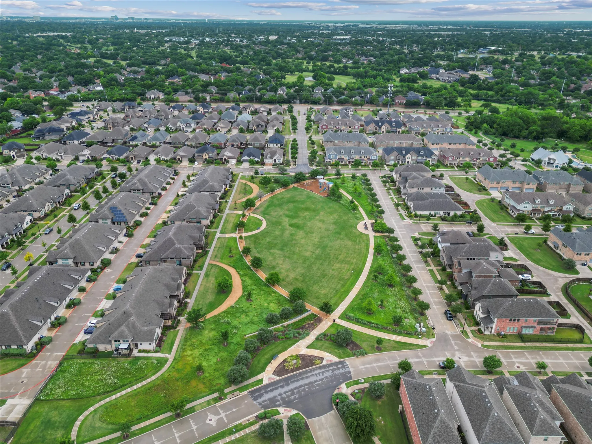 Expansive green space with walking paths surrounded by residential properties