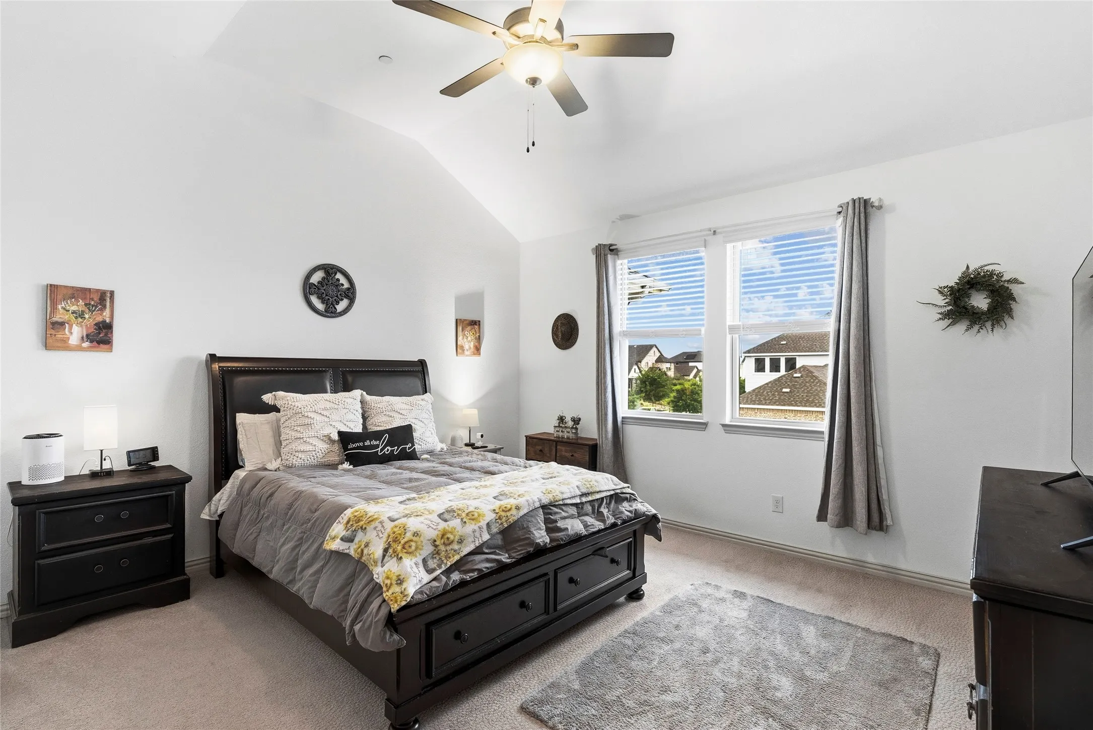 Vaulted ceiling with an attached ceiling fan, dual windows with blinds, and neutral carpeting