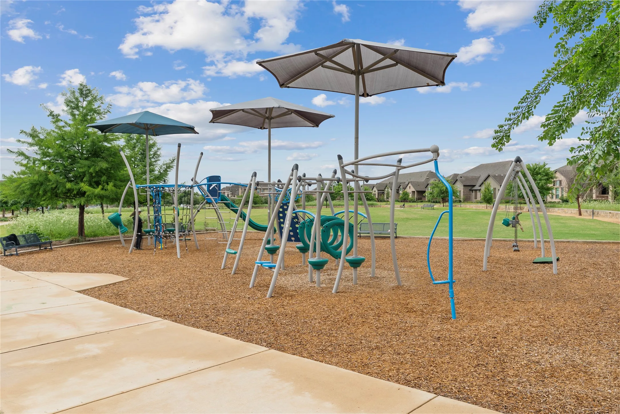 Outdoor recreational area featuring multiple play structures, swings, and shade canopies