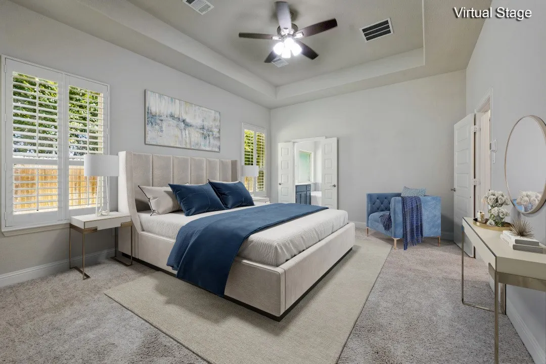Virtually staged primary bedroom. There is built in wiring for a TV on the wall above the blue chair.
