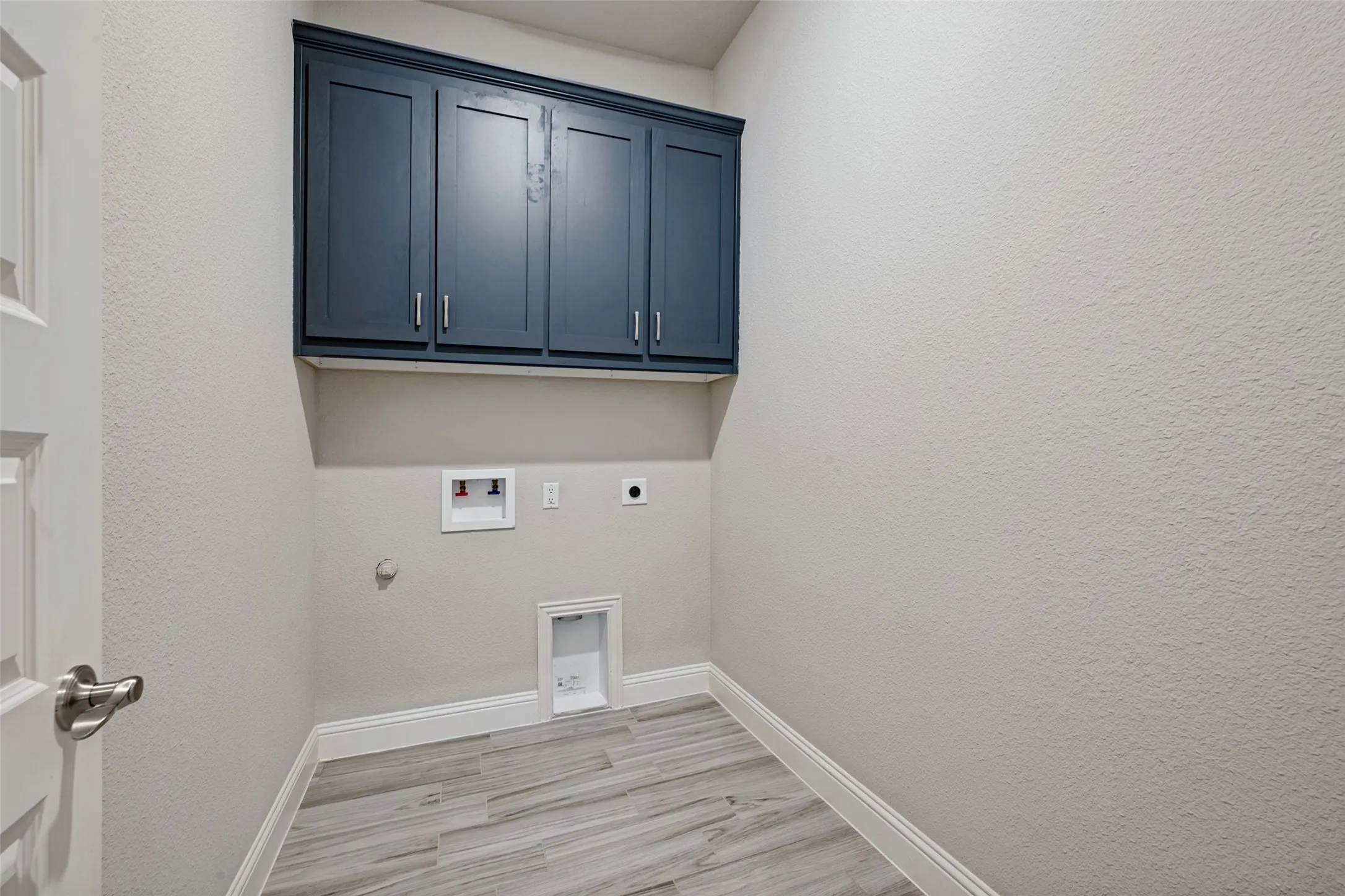 Built-in cabinetry with dark blue shaker-style cabinets help to conceal all your laundry supplies.