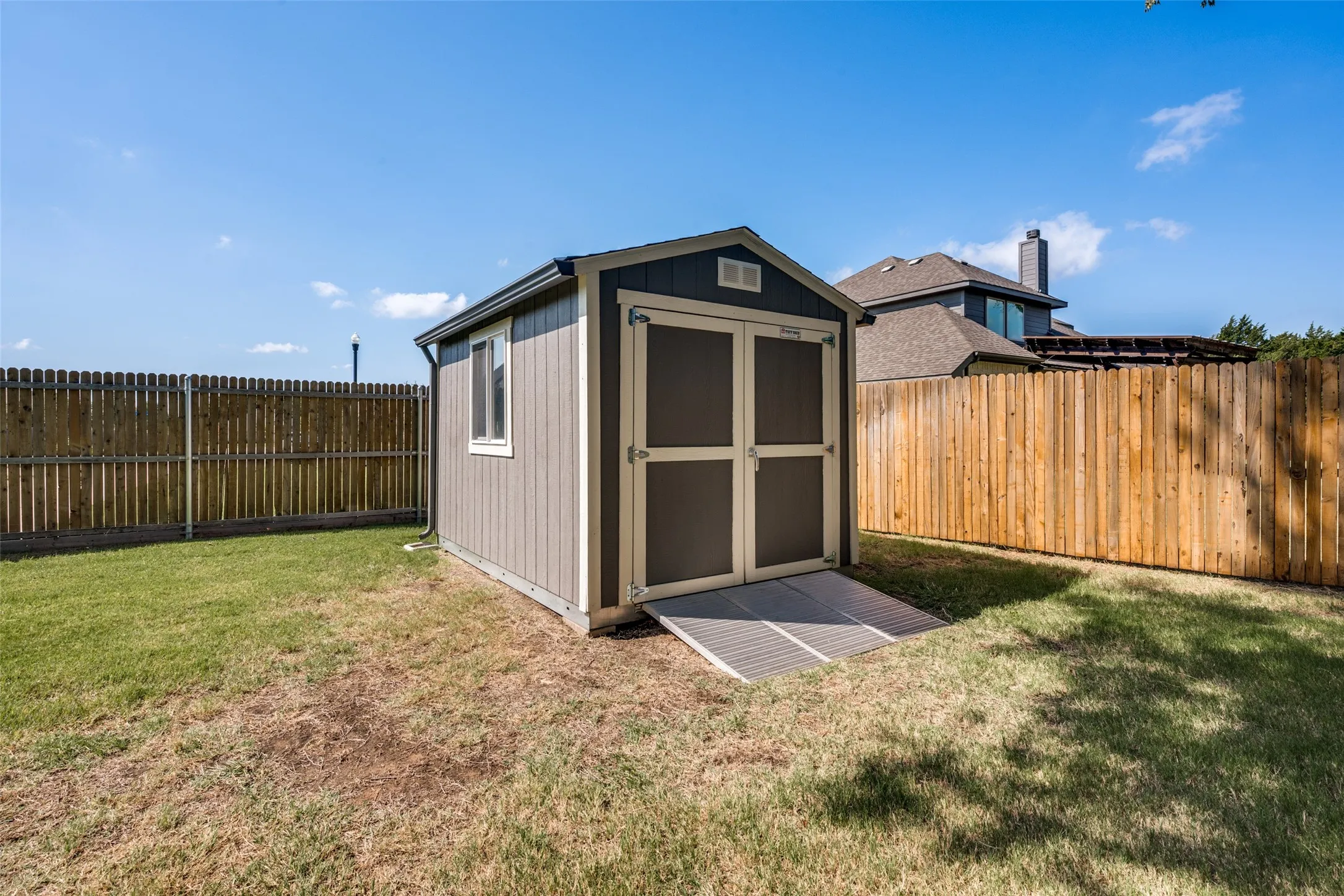 Top quality Tuff Shed for storing your lawn mower and tools was painted to match the main house. It has gutters, a window and sits off the ground on a metal foundation.  Notice the oversized ramp for easier access.