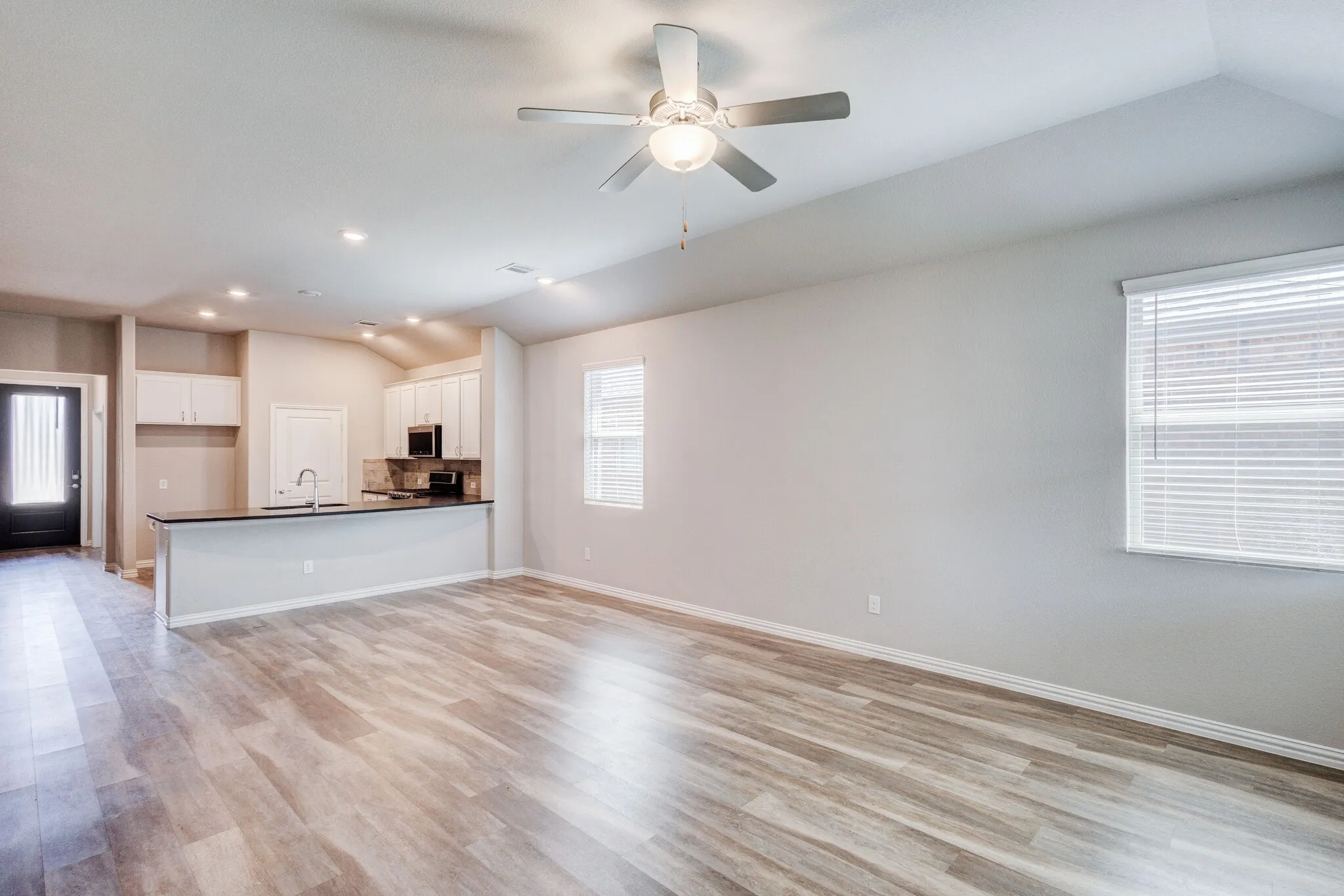 Open concept living space with wood-finish flooring, vaulted ceiling, and recessed lighting