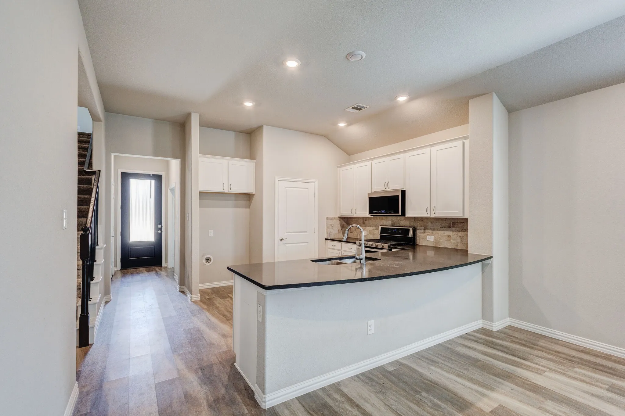 Kitchen featuring white cabinetry, stone-look backsplash, built-in microwave, and a gas range